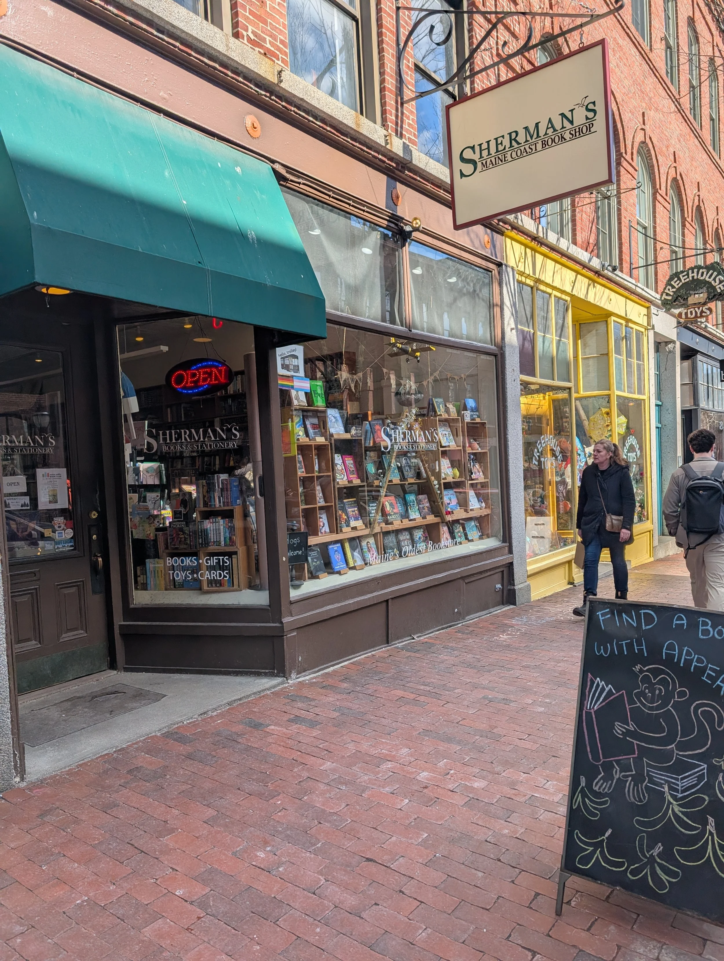 Nineteenth-century brick building with glass storefront and brick sidewalk with a-frame sign out front