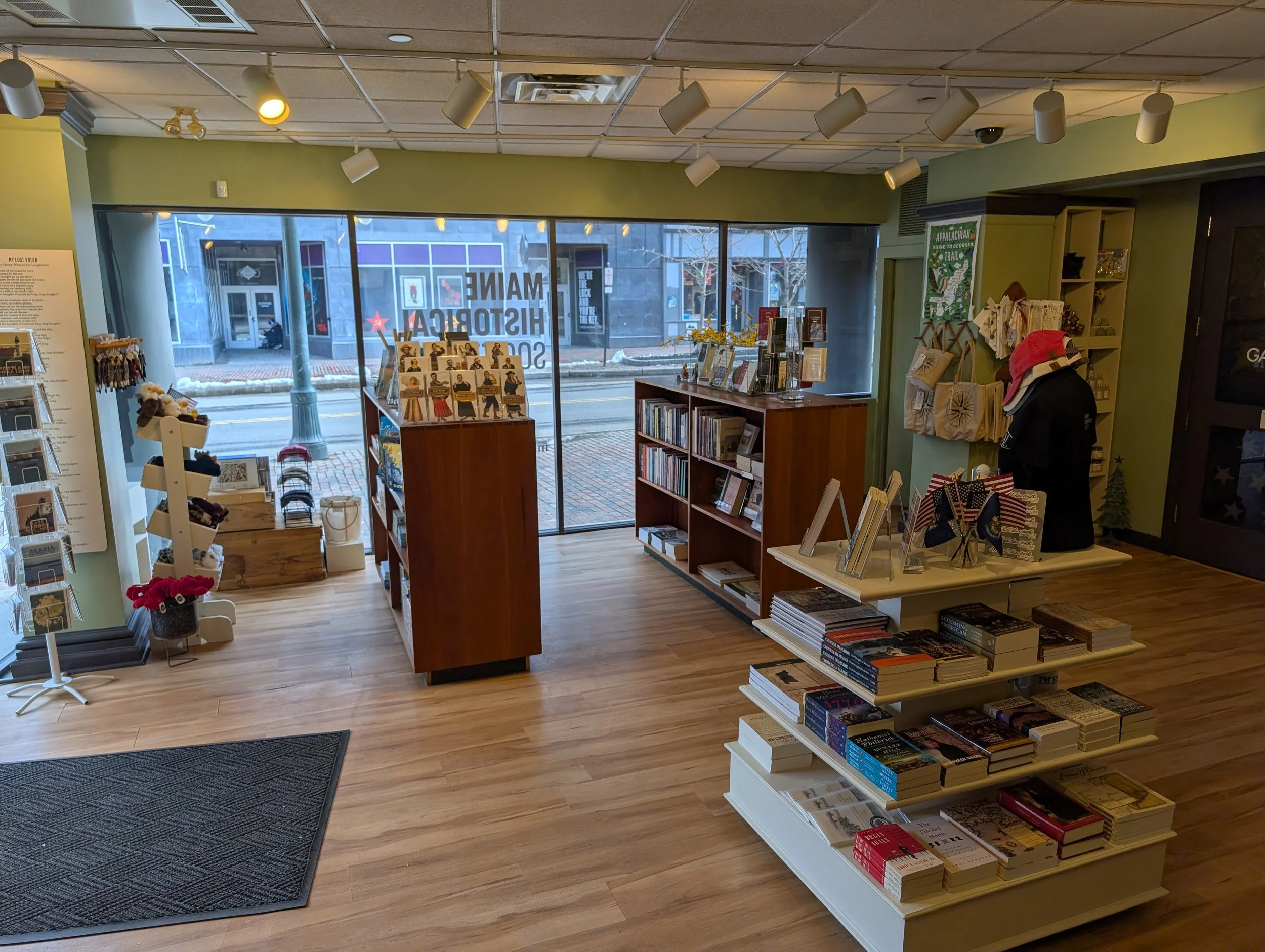 A sunny, airy room with wooden floor and shelves stocked mostly with books