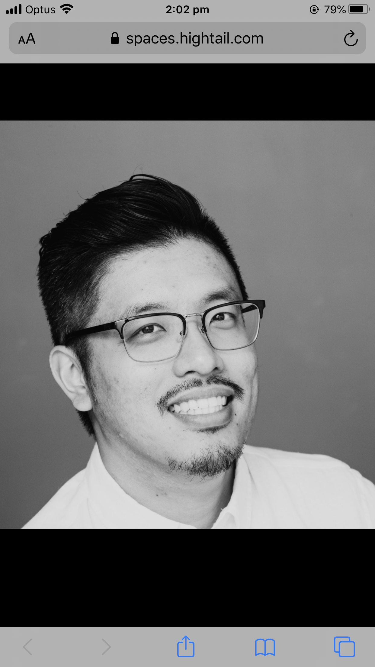 Black and white portrait of a smiling man with glasses, facial hair, and neatly styled hair, wearing a collared shirt.