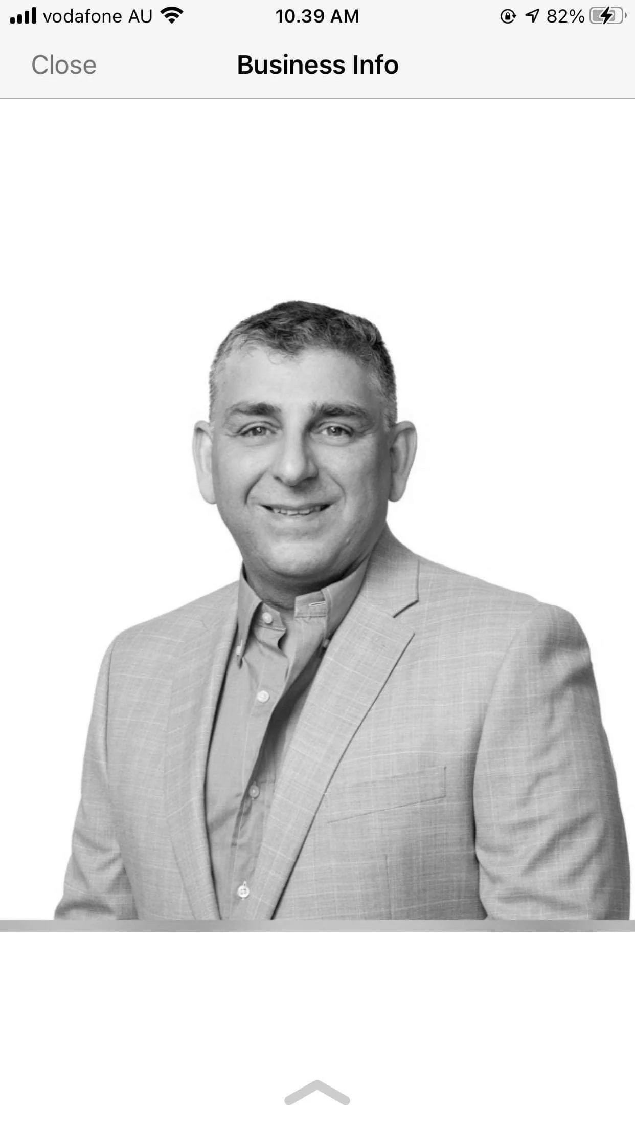 Black and white professional headshot of a man in a suit and shirt, smiling.