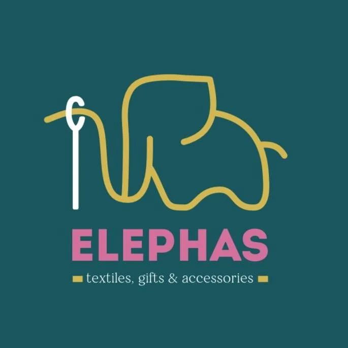 Logo for Elephas, featuring a yellow outline of an elephant holding a cane with a pink and white text reading 'ELEPHAS' and smaller text below saying 'textiles, gifts & accessories'.