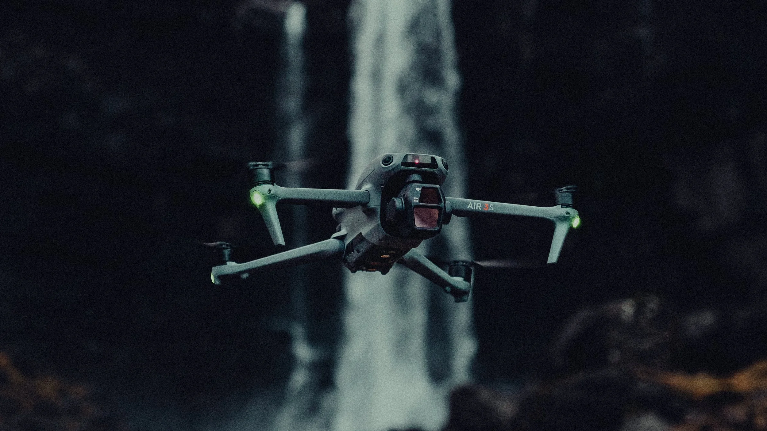 Drone flying in a dark cave with a waterfall in the background
