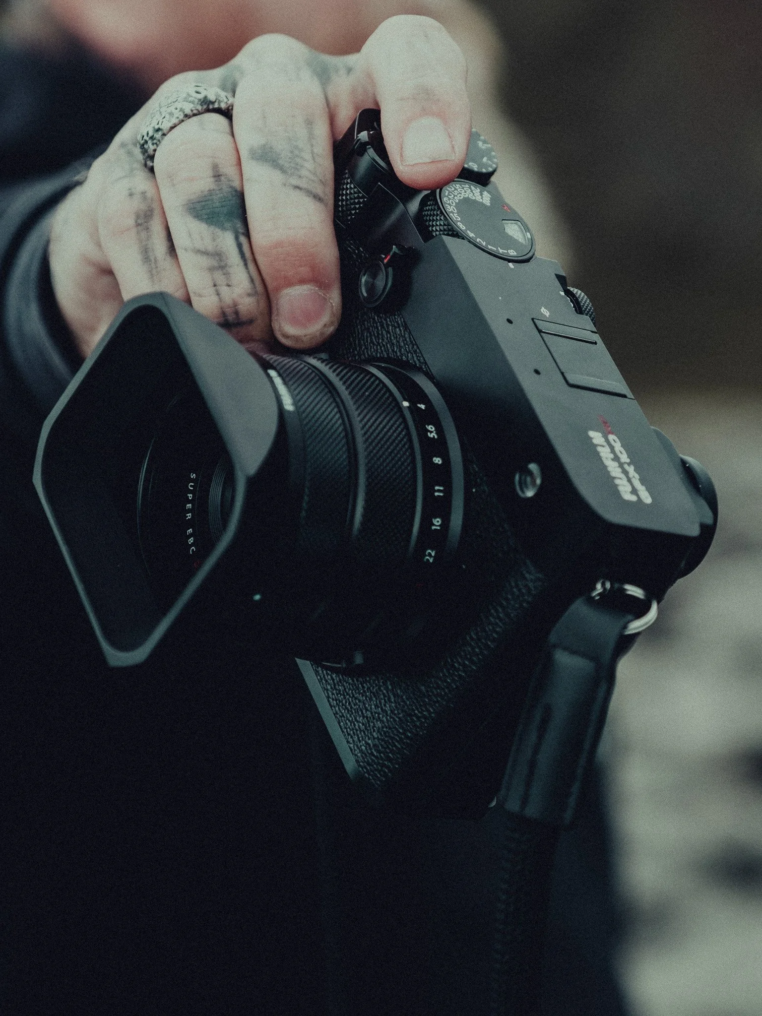 Close-up of a person's hand holding a black digital camera with a zoom lens.