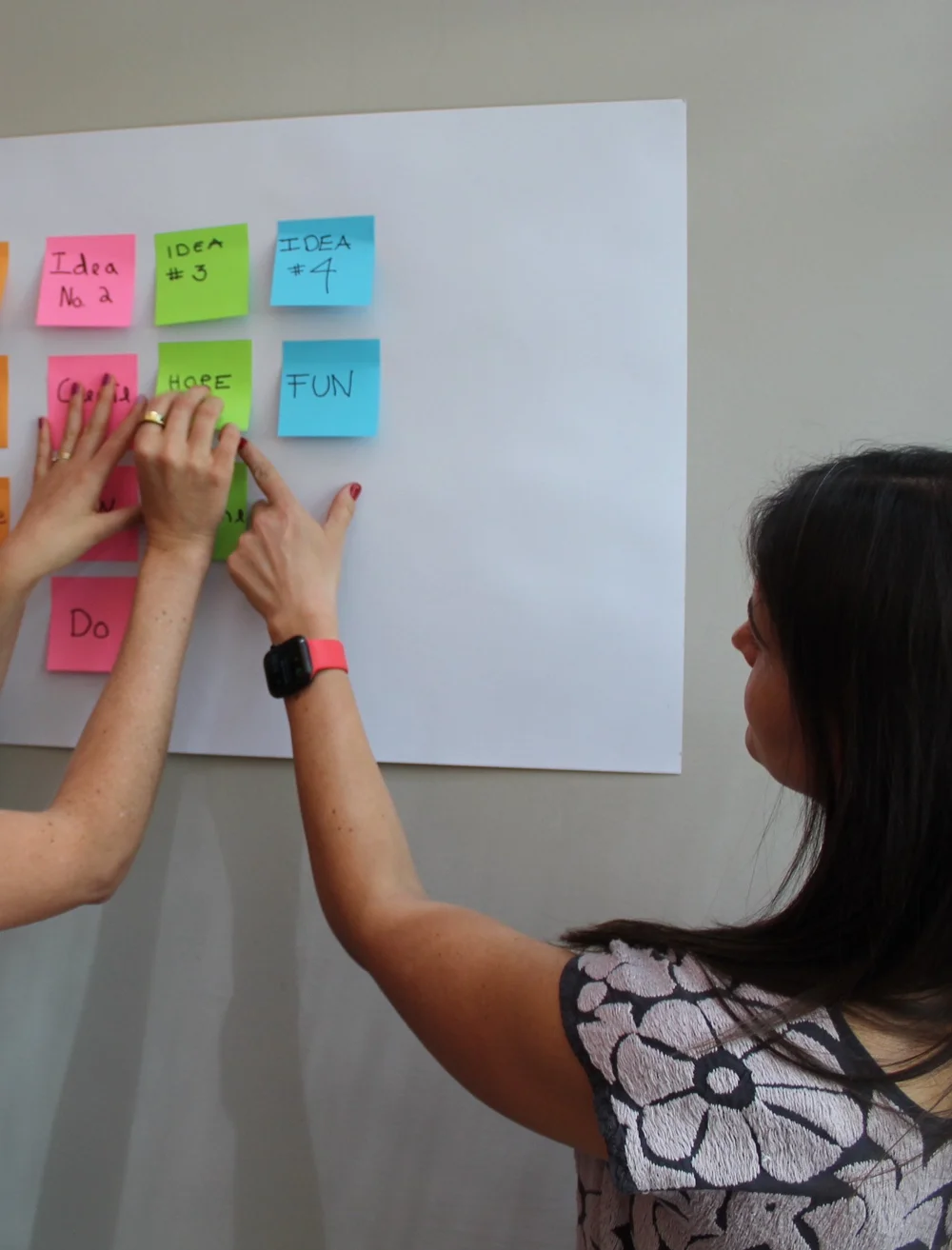 Manos organizando notas adhesivas durante una sesión de co-creación