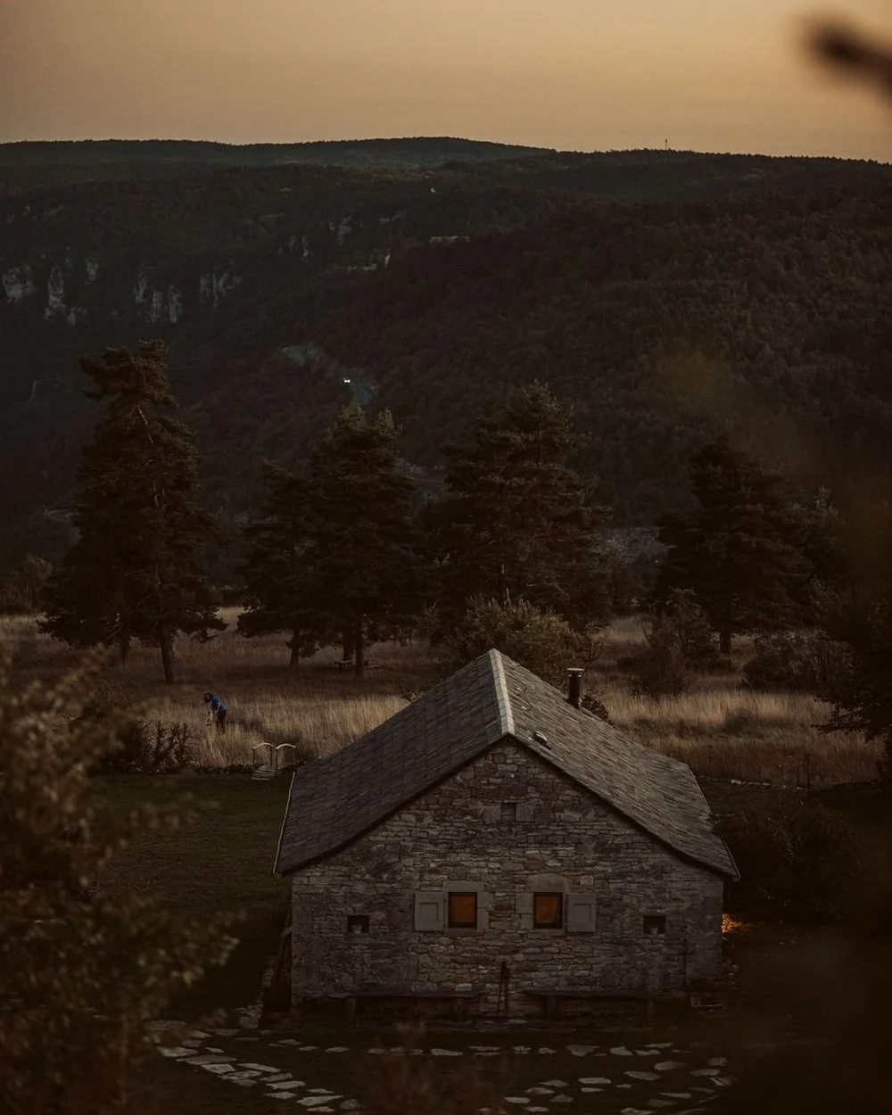 Stone farmhouse at dusk with warm lit windows at L'Esprit d'Almières, evening at Casa Retreats France