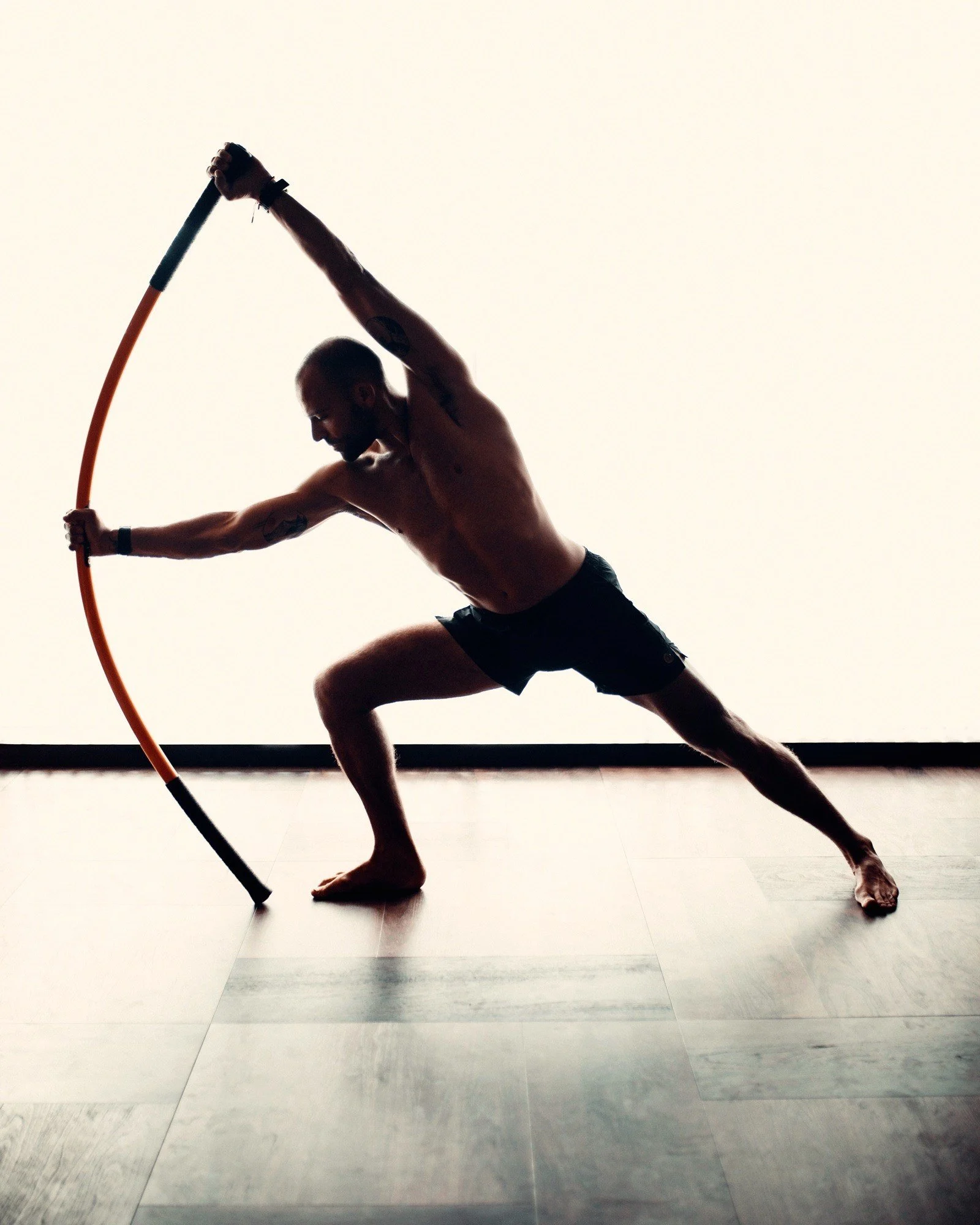 Casa Retreats movement specialist Danny Ciccolini demonstrating a lateral mobility exercise with an orange training stick