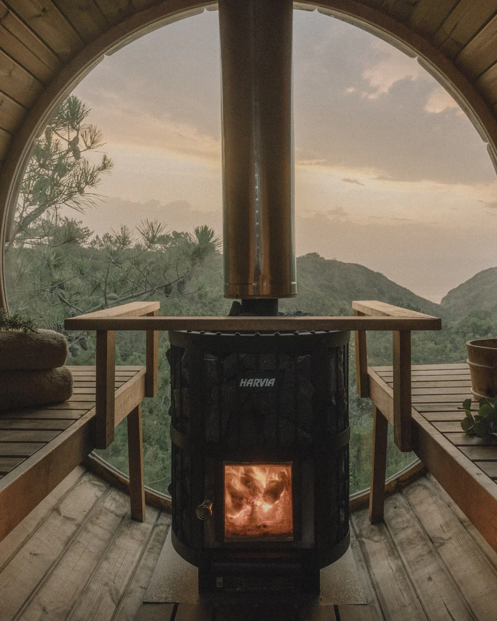 Interior of Amaria’s wood-fired barrel sauna, with timber benches and coastal hills visible through its circular window near Odeceixe, Portugal