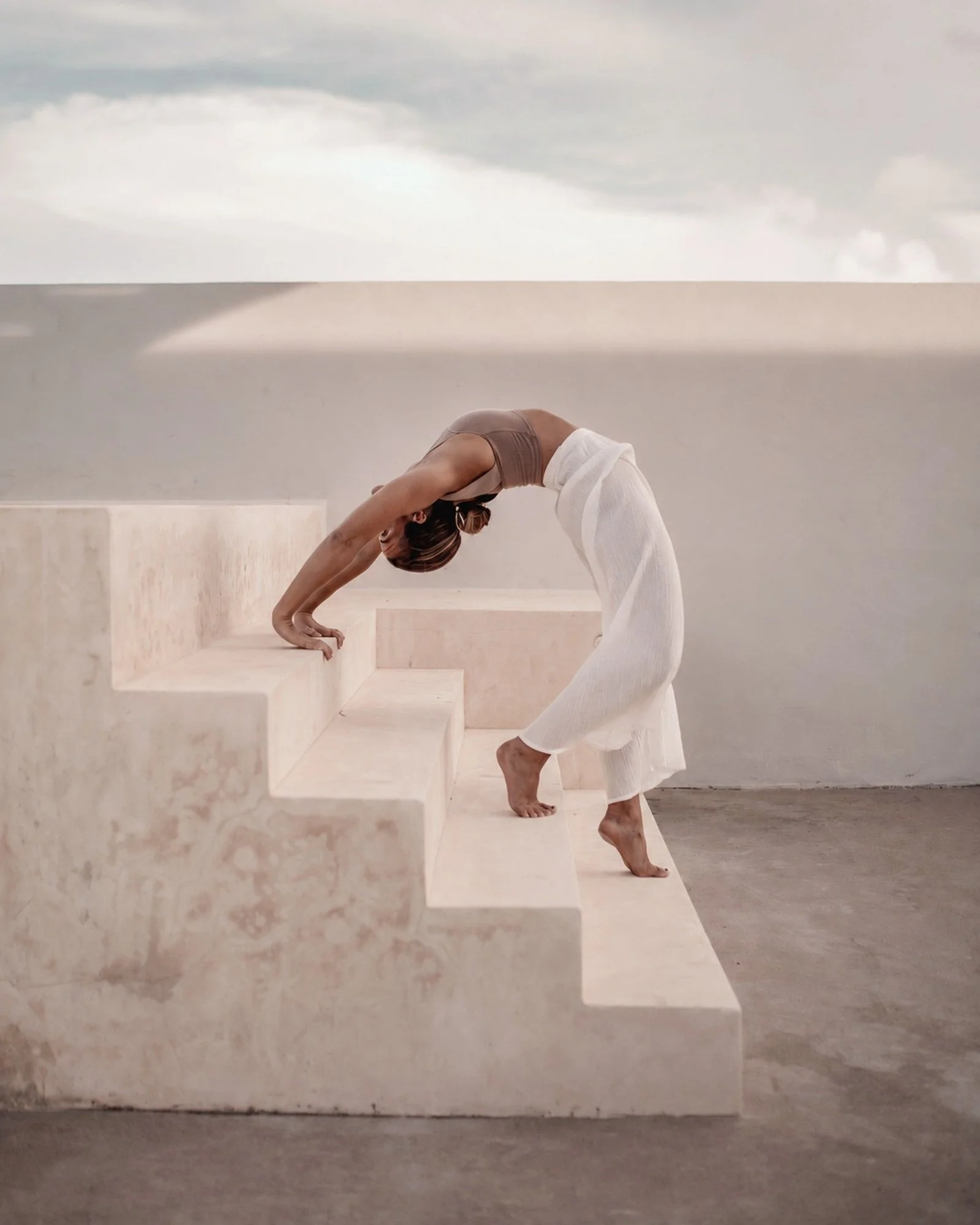 Casa Retreats founder Lauren Coleman moving through a standing backbend on pale stone steps