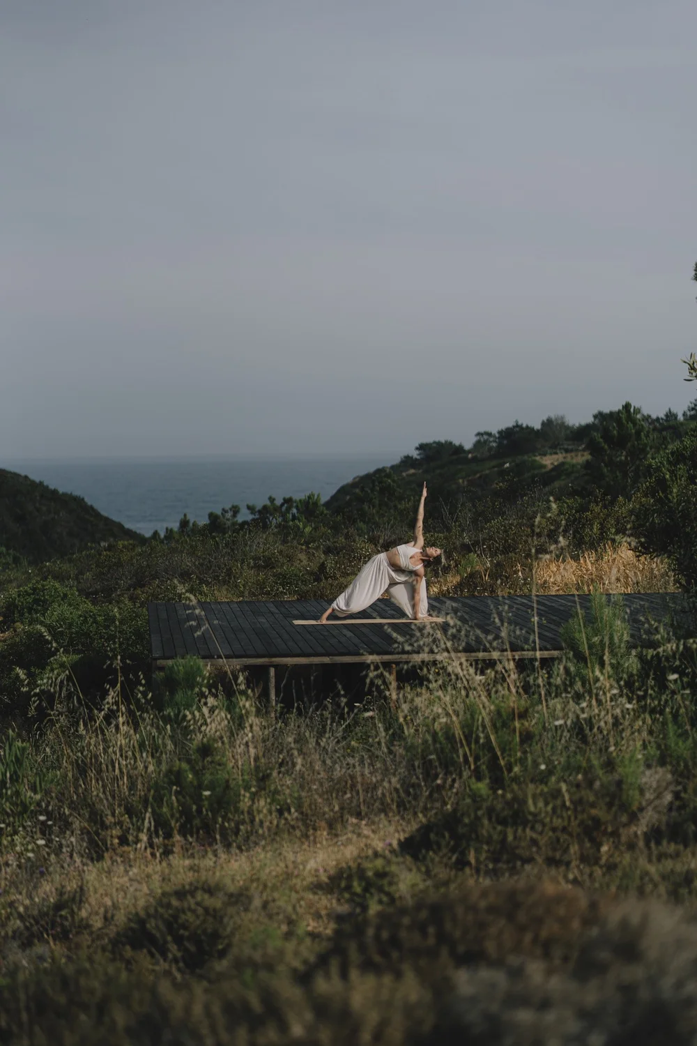 Woman practising yoga on an outdoor deck overlooking the Atlantic at Amaria near Odeceixe, Portugal