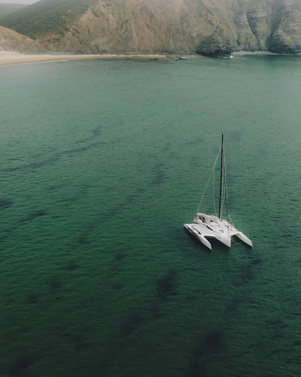 A sailing catamaran at anchor in a sheltered bay on the Algarve coast near Lagos, Portugal