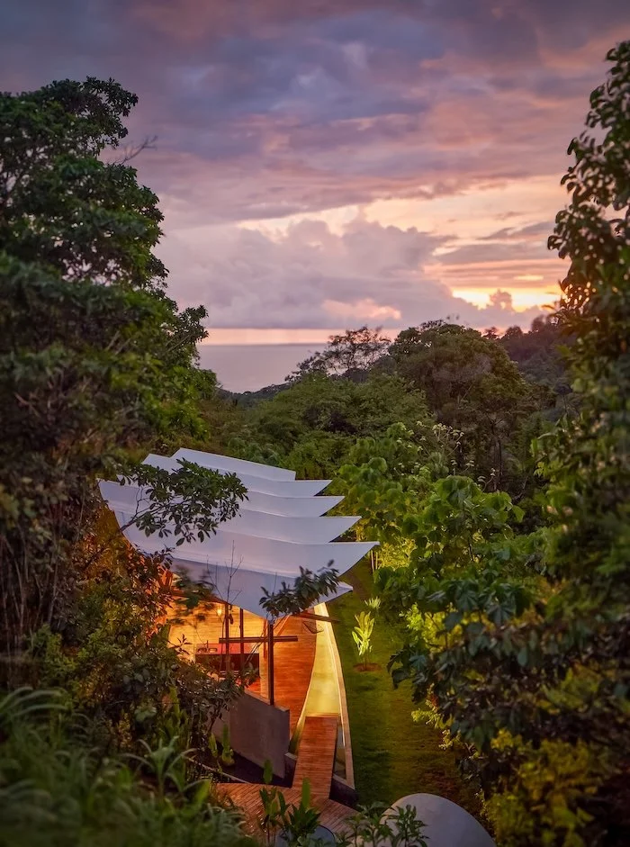 Open-air jungle yoga shala with teak flooring and canopy views—primary practice space in Uvita.
