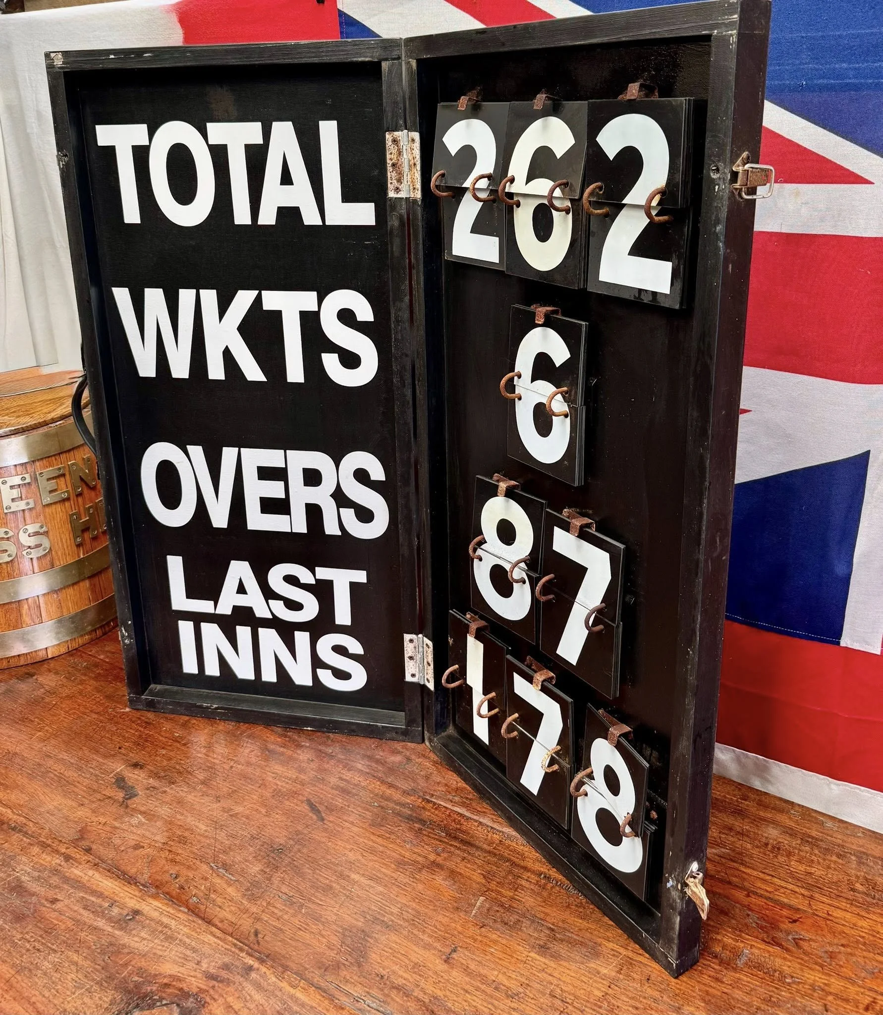 A black vintage-style changeable sign with white letters and number panels displays a total of 282. Behind it, part of an American flag is visible, and the sign is placed on a wooden floor.