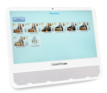 CareLink 360 device displaying a karaoke song selection, including titles like "I Walk the...," "Sweet Heart," "Stand by Me," and "Love Me Tender," with thumbnail images of individuals singing or posing.