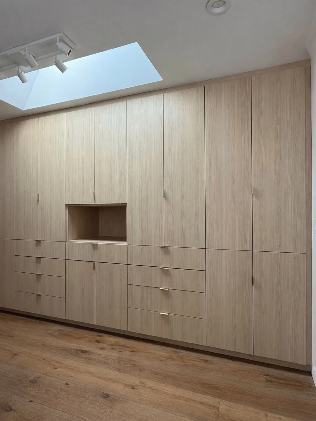 Bedroom built-in cabinets featuring lighted rods and glass shelves