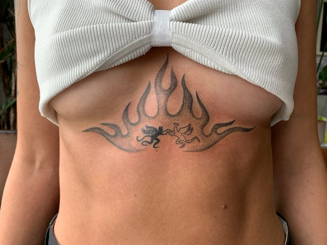 Tattoo of a black dragon and flowing flames on a person's chest.