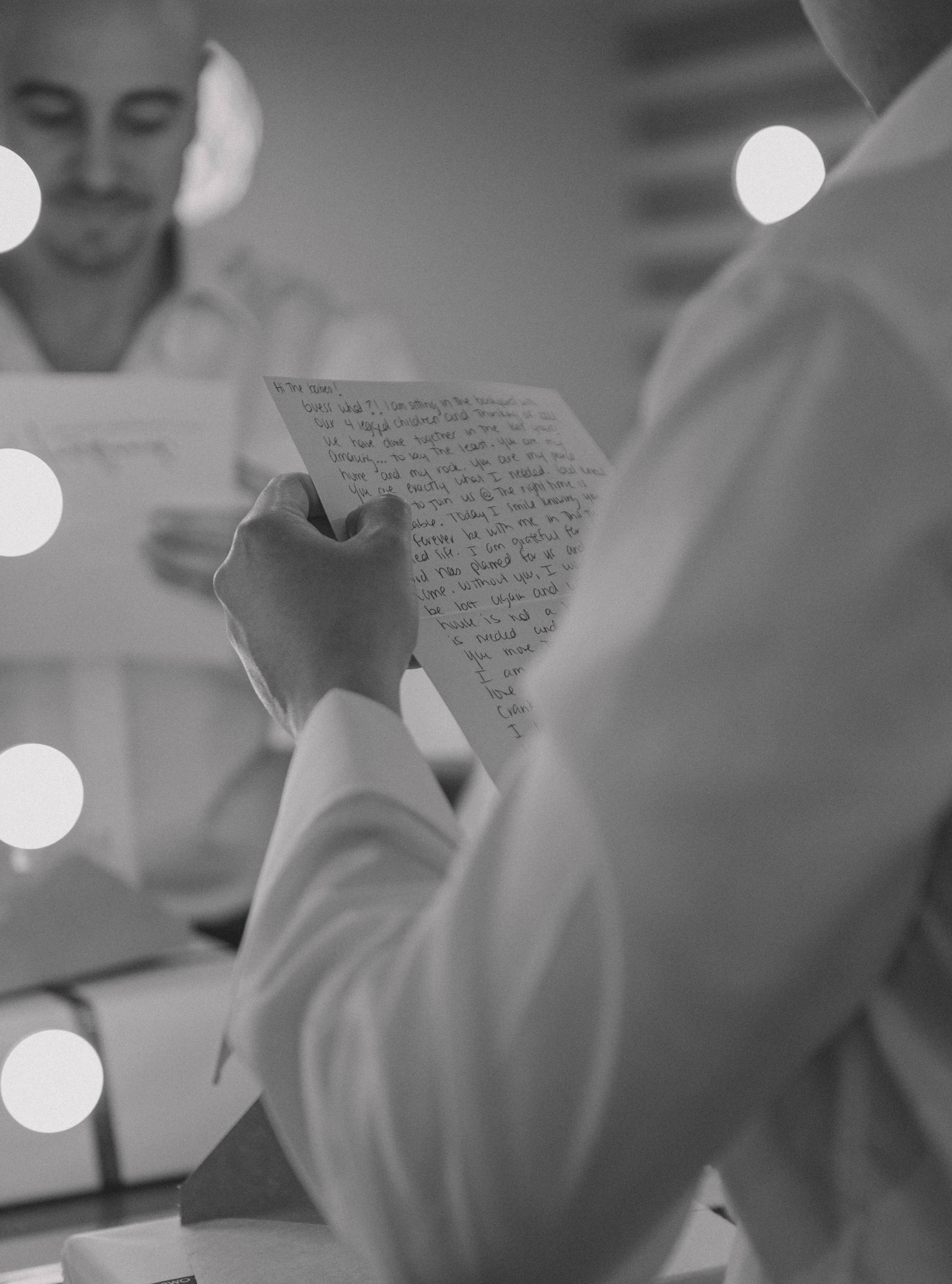 Two people in formal attire exchange handwritten letters in a softly lit room.