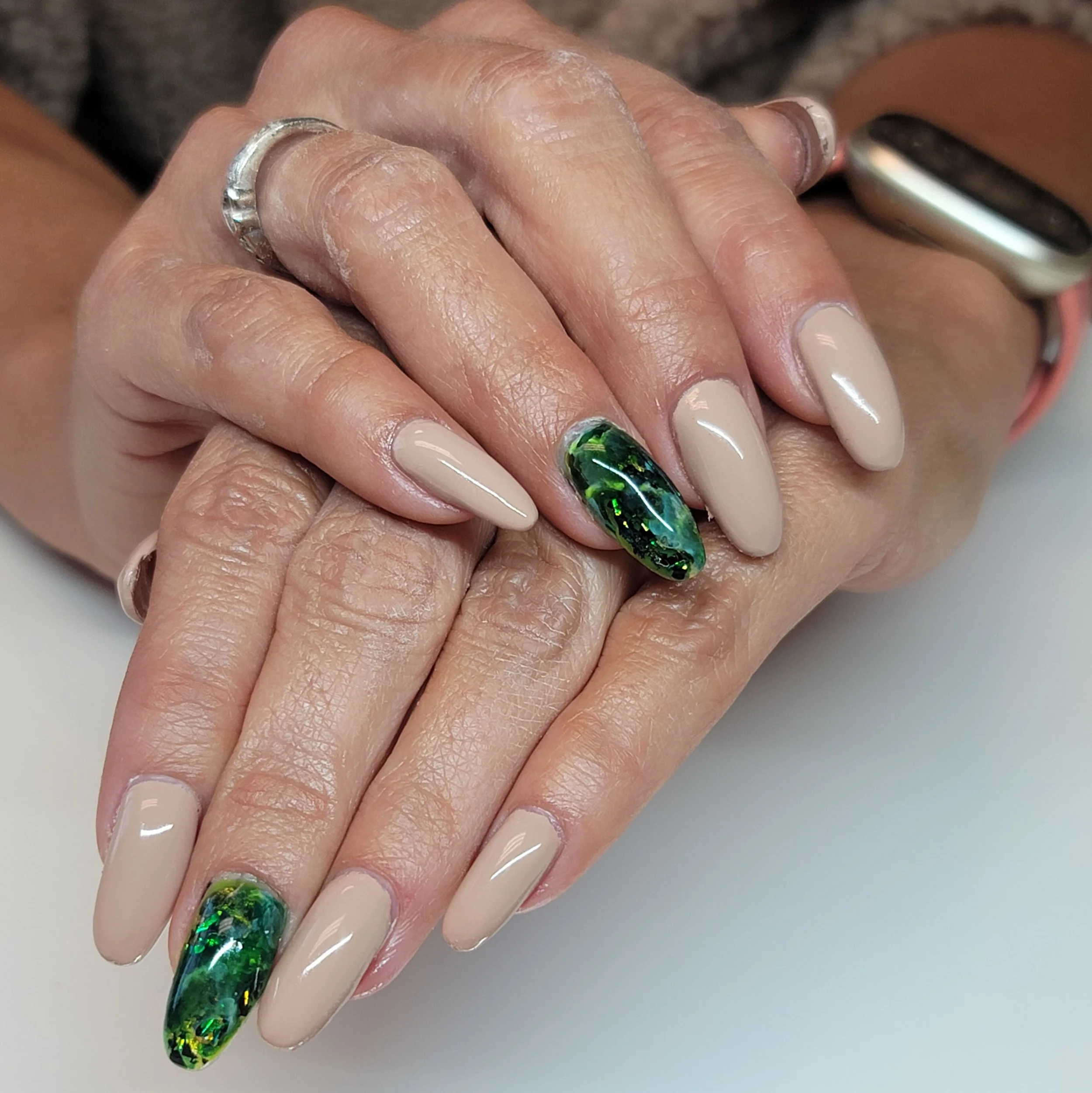 Emerald accent nails with nude nails.