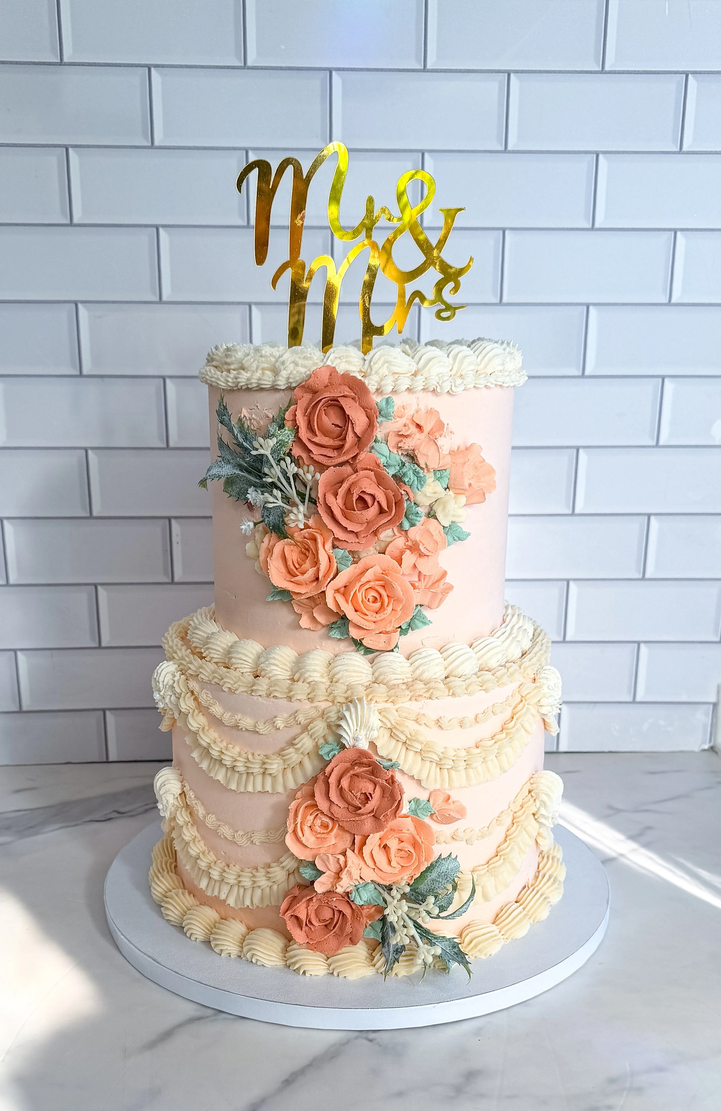 Two-tier vegan wedding cake in vintage style piping, florals and peach tones by Veg on Board for a wedding at The American Hotel in Sag Harbor, NY