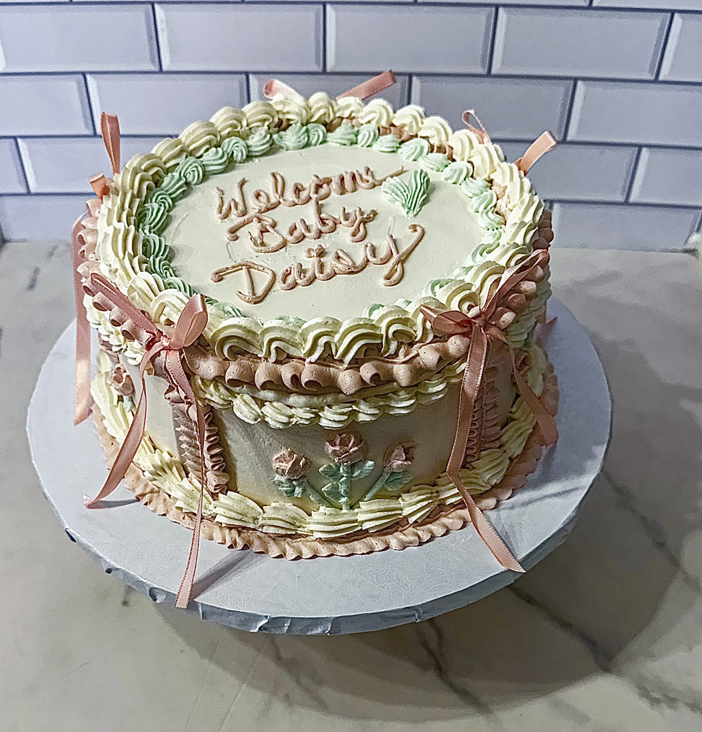 vegan vintage cake design for baby girl with pink ribbons, bows, buttercream swags and shells