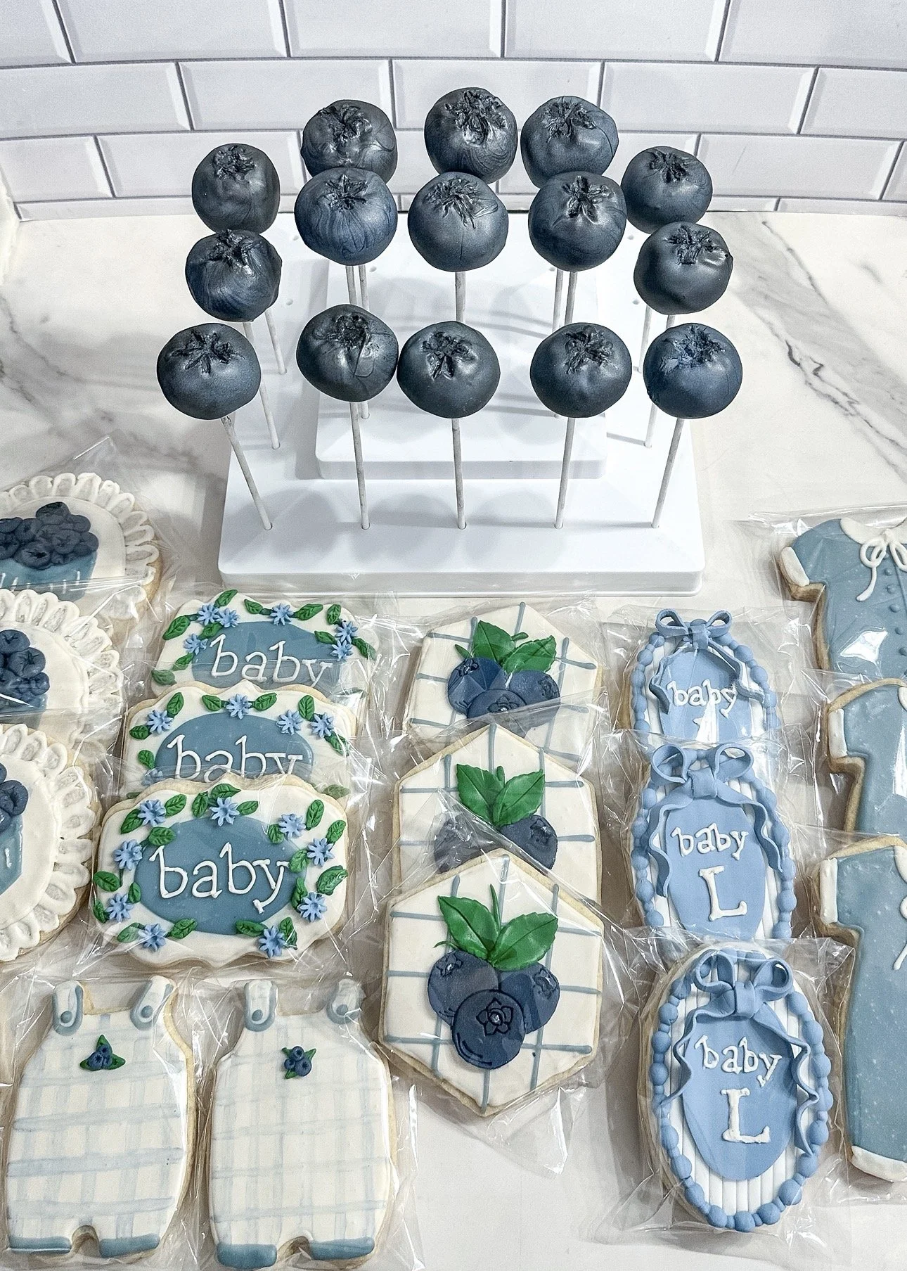 vegan baby shower dessert display with blueberry shaped cake-pops and custom decorated cookies