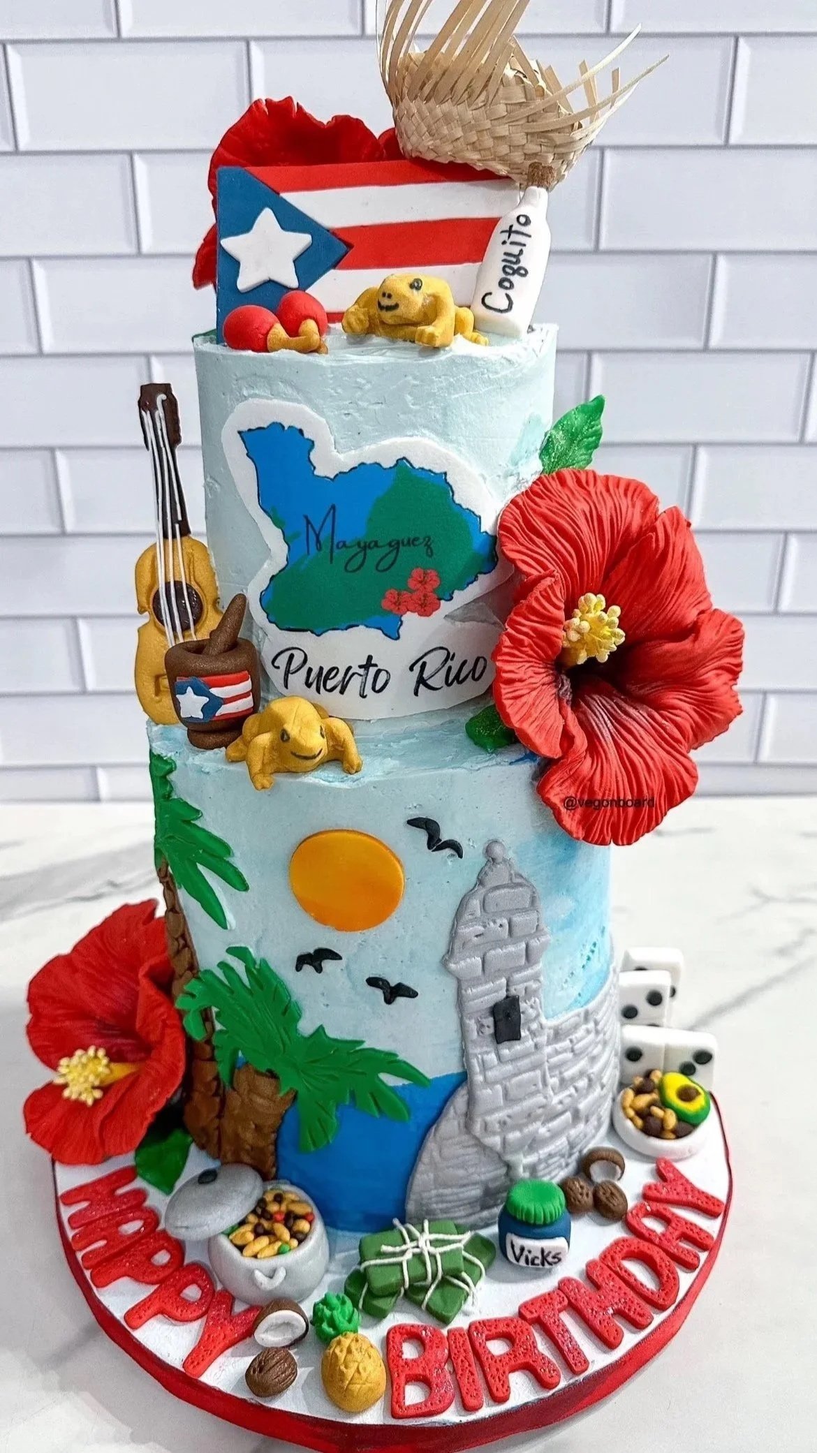 Two-tier vegan Puerto Rico themed cake with fondant sculpted decor of Puerto Rico culture made by Veg on Board