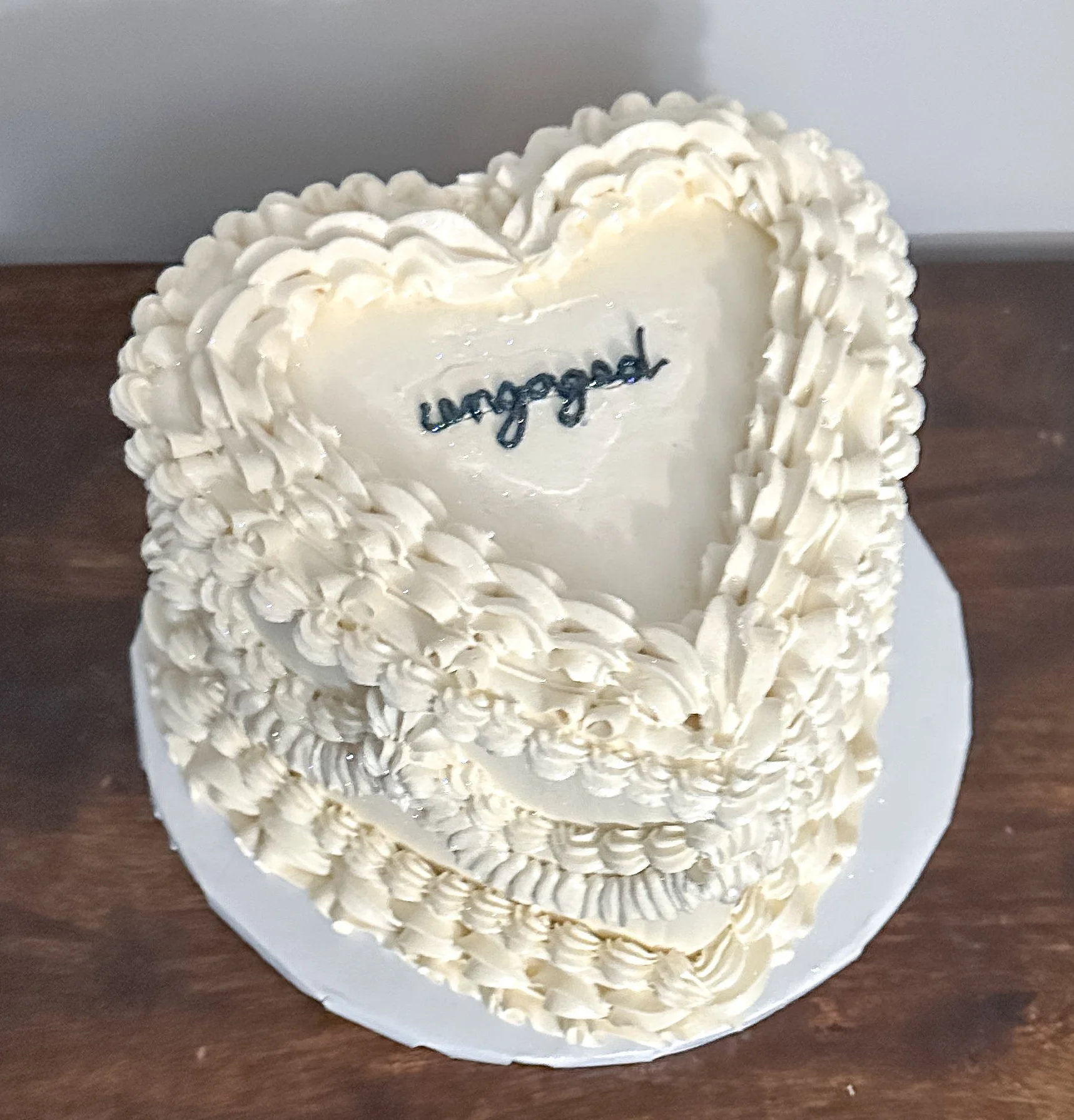 vegan and gluten-free heart shaped engagement cake with vintage style piping and engaged piped on top in black buttercream