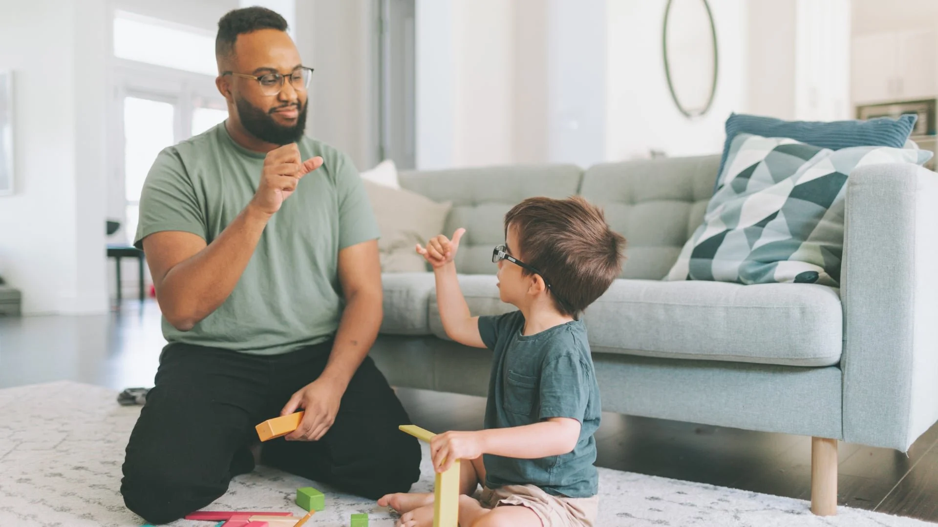 Therapist teaching sign language to child during playtime—supporting communication development in a home-based learning environment.