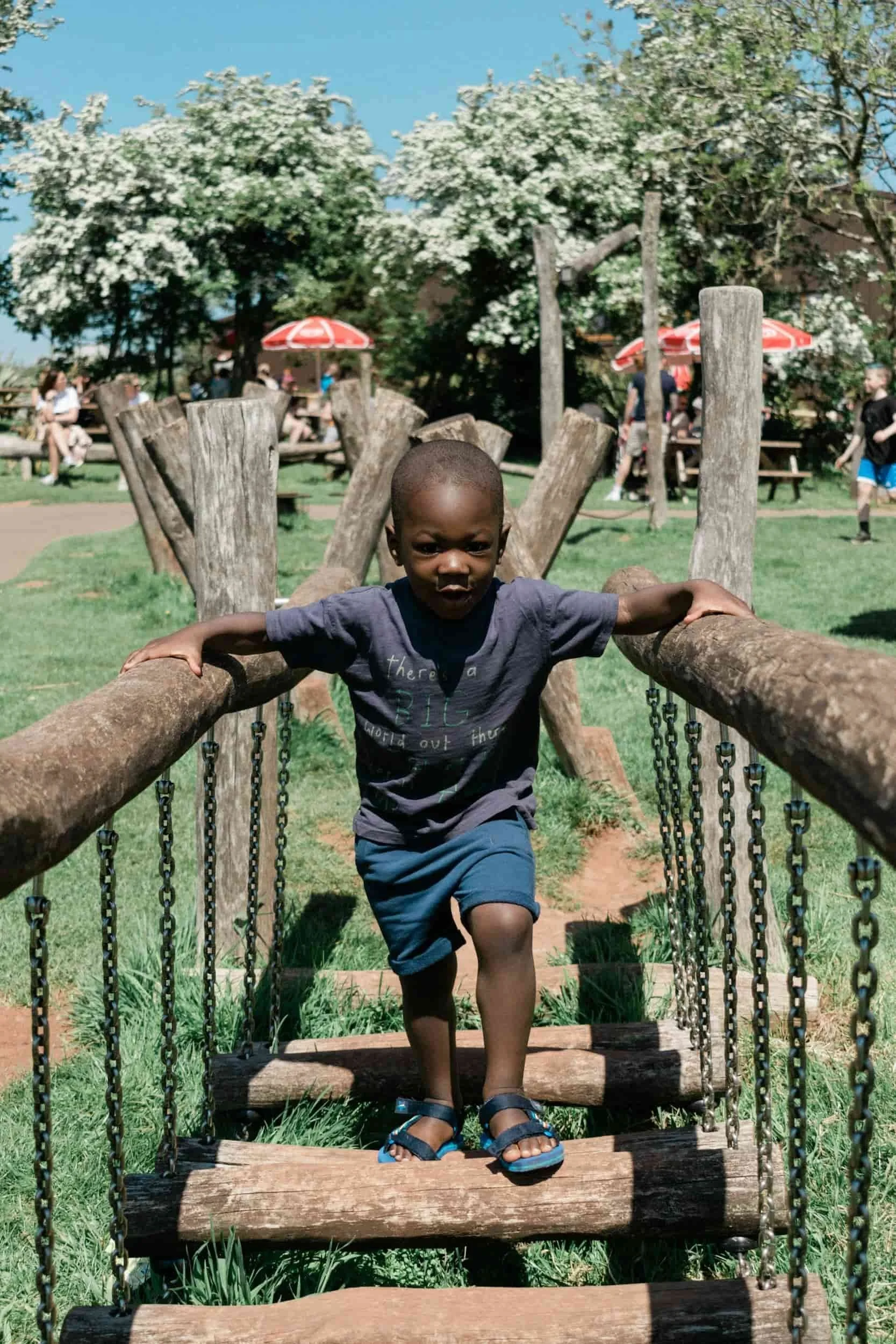 Child building balance and coordination on a rope bridge—outdoor gross motor activity supporting strength and sensory development