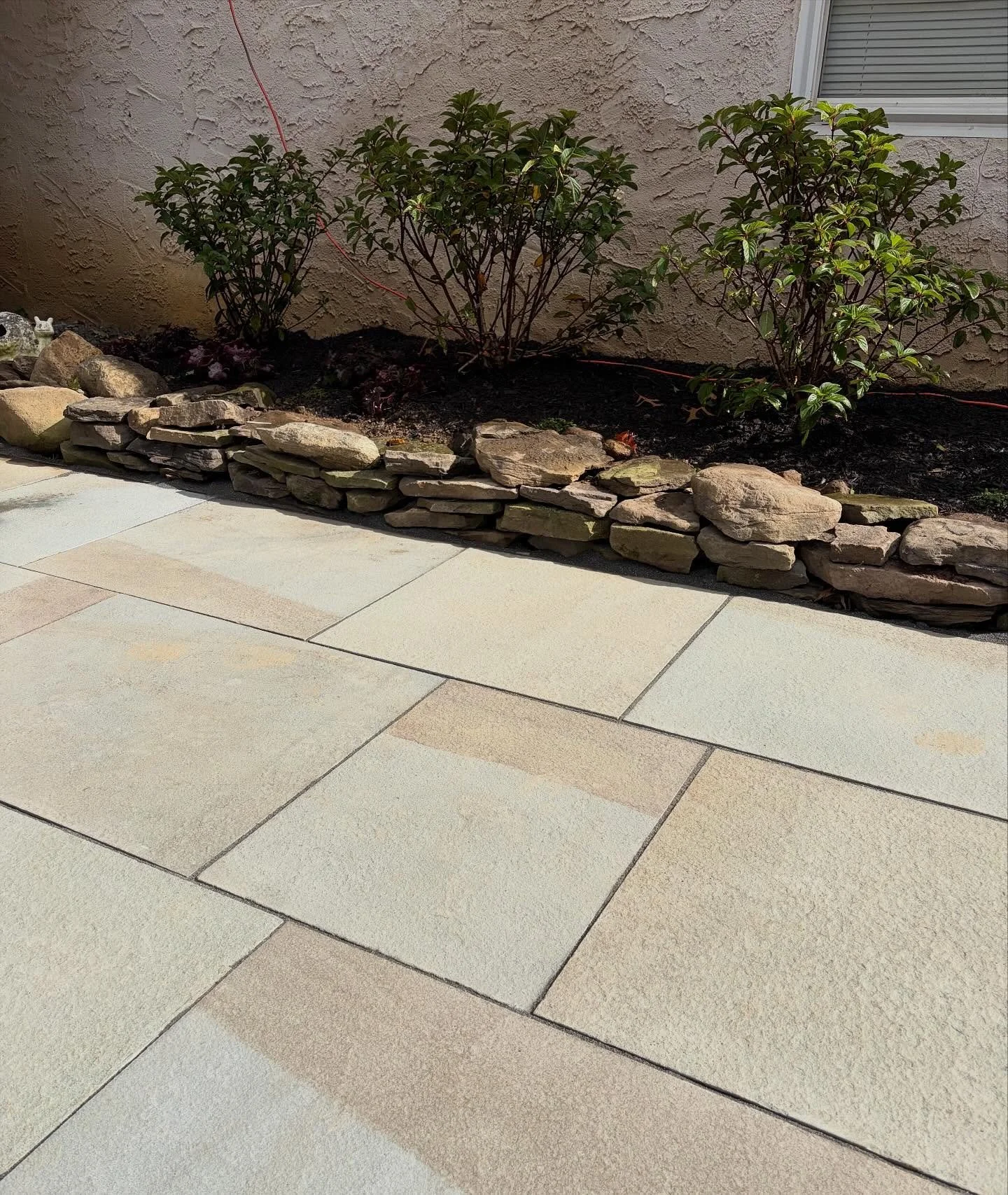 New bluestone patio, mini dry stone wall and a neat row of Paniculated Hydrangeas make for a calm and cozy gathering place, just in time for fire pit season!  Scroll right for the before picture.