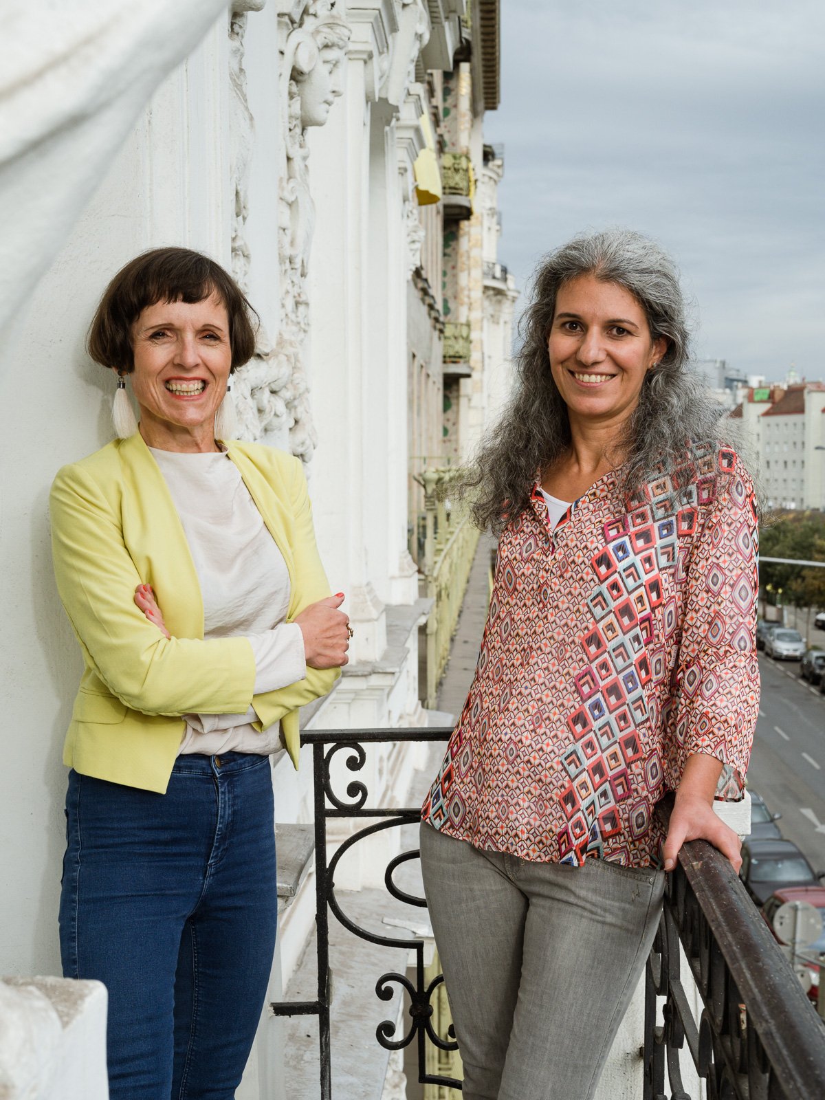 Portrait Gertraud Leimüller und Rania Wazir auf einem Balkon mit Ausblick auf eine Straße