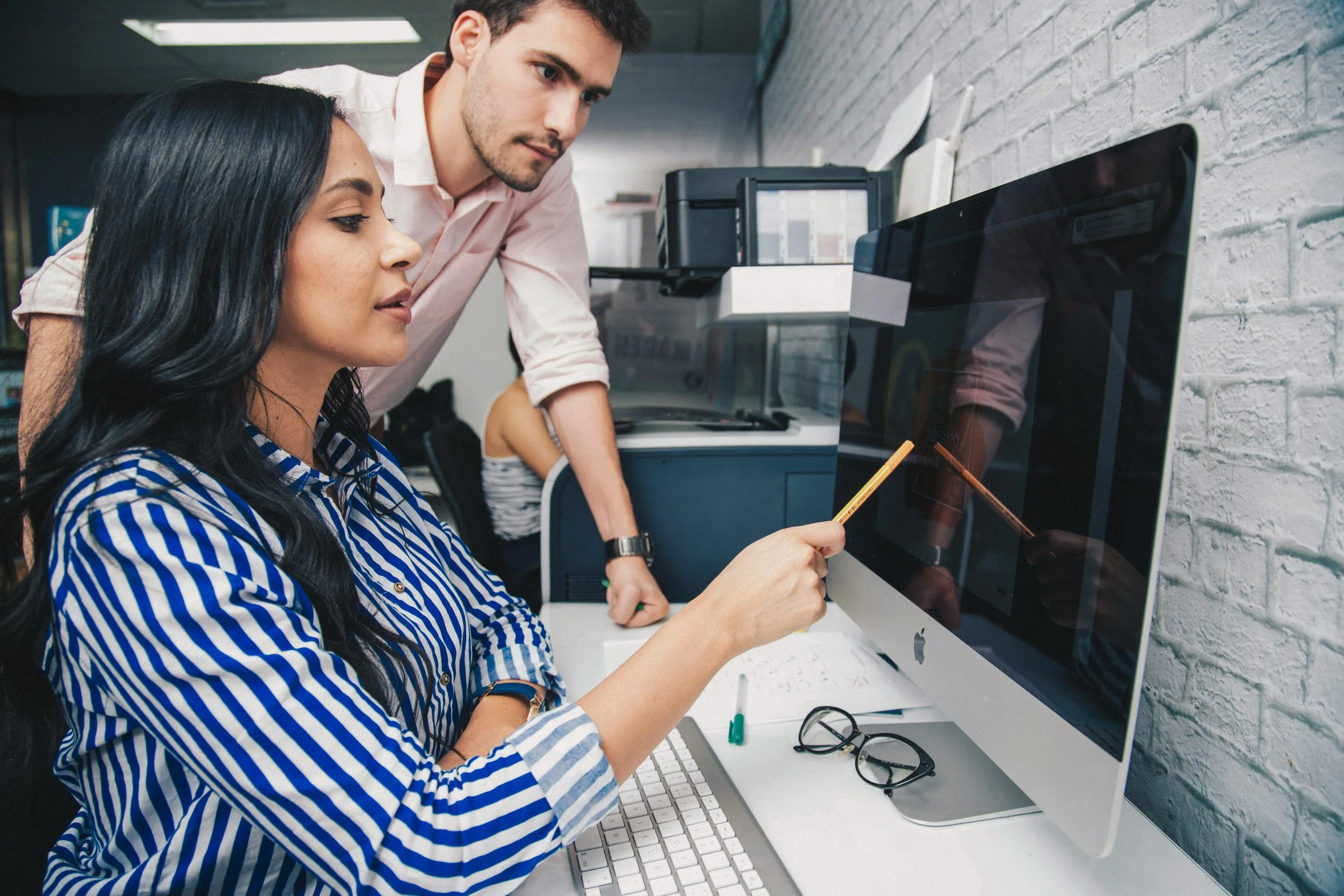 Two employess working together on a problem, looking at a screen
