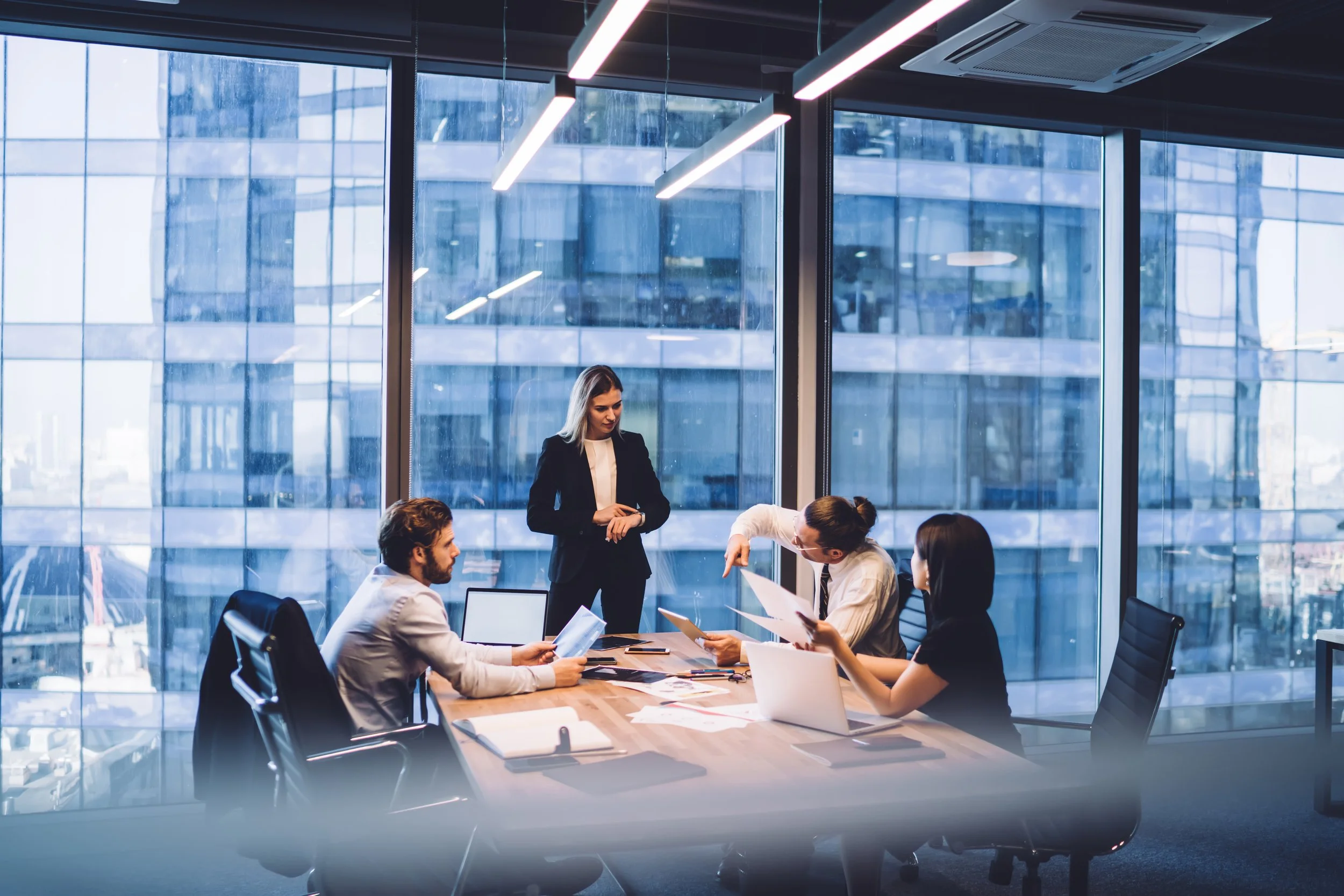 A group of people in a meeting at an office in front of large windows