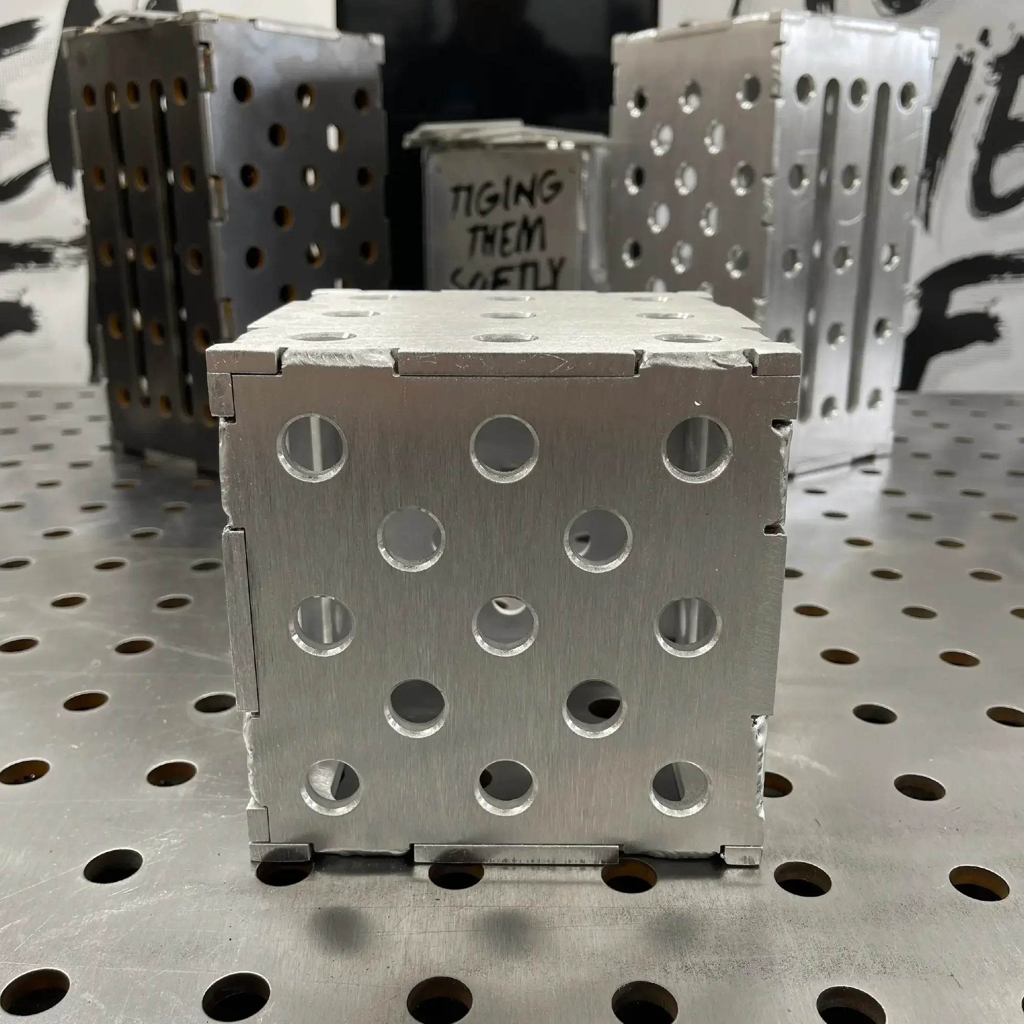 Front view of assembled aluminium TIG Fixture Cube — multiple clamp holes and IA-FAB branding