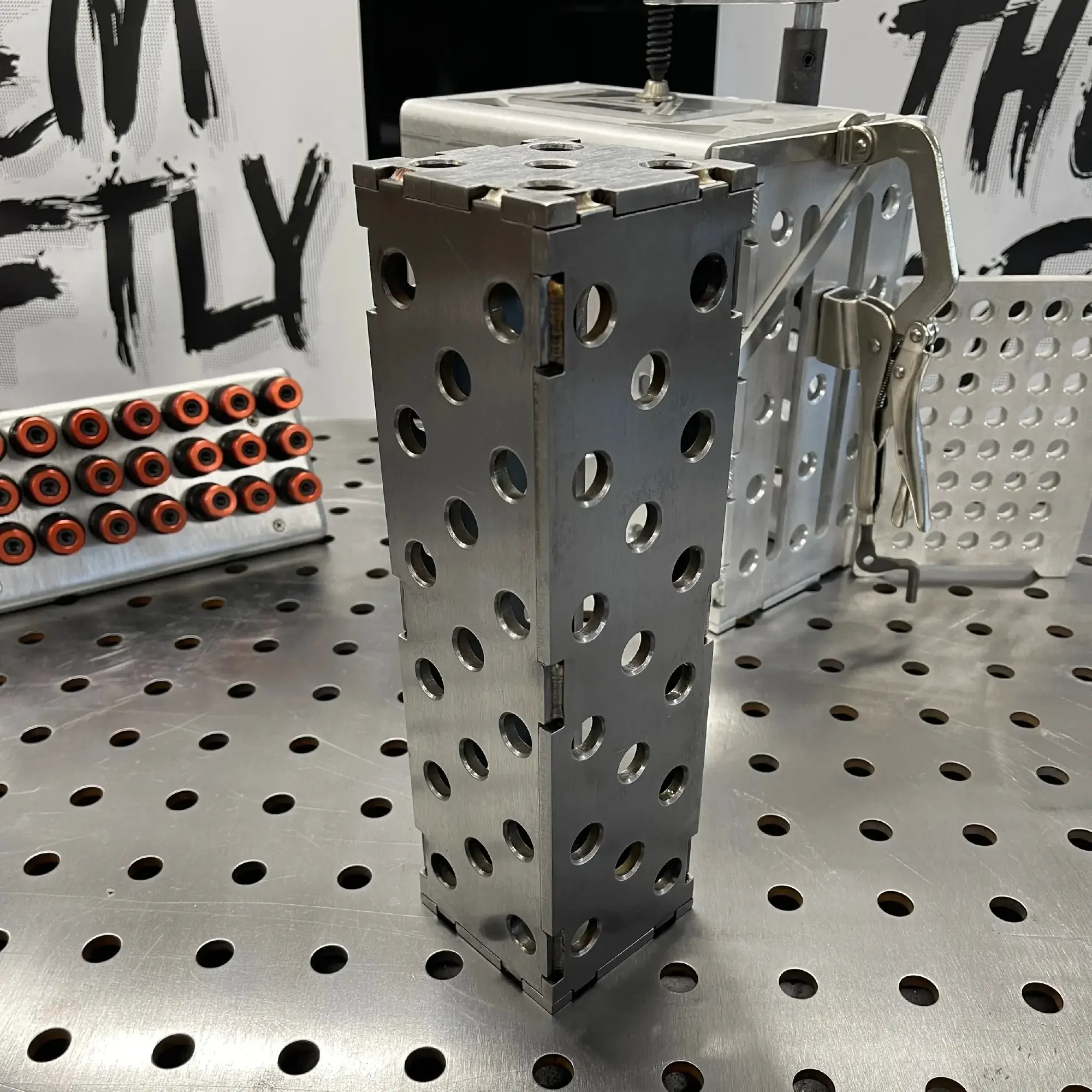 Steel Slim Riser Block brushed finish – vertical fixture setup on perforated welding table