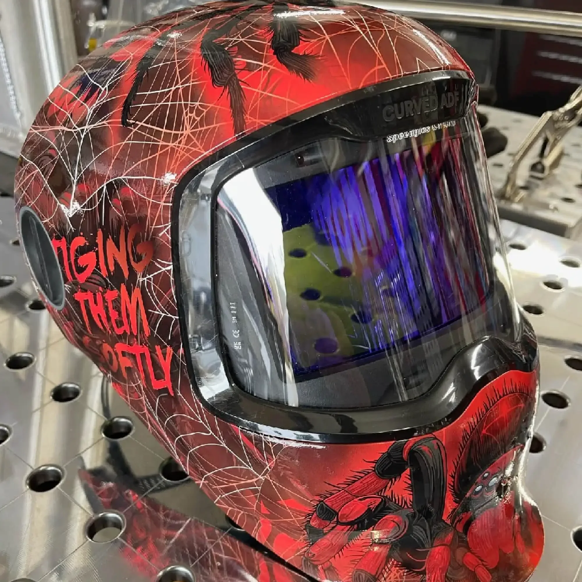 Tiging Them Softly Arachnid-X welding helmet wrap — red and black vinyl design featuring spider and web graphics for bold custom welding hoods.