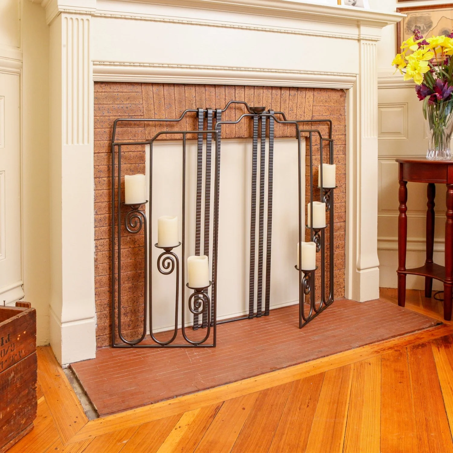 Summer screen resting in front of a closed fireplace with white pillar candles 