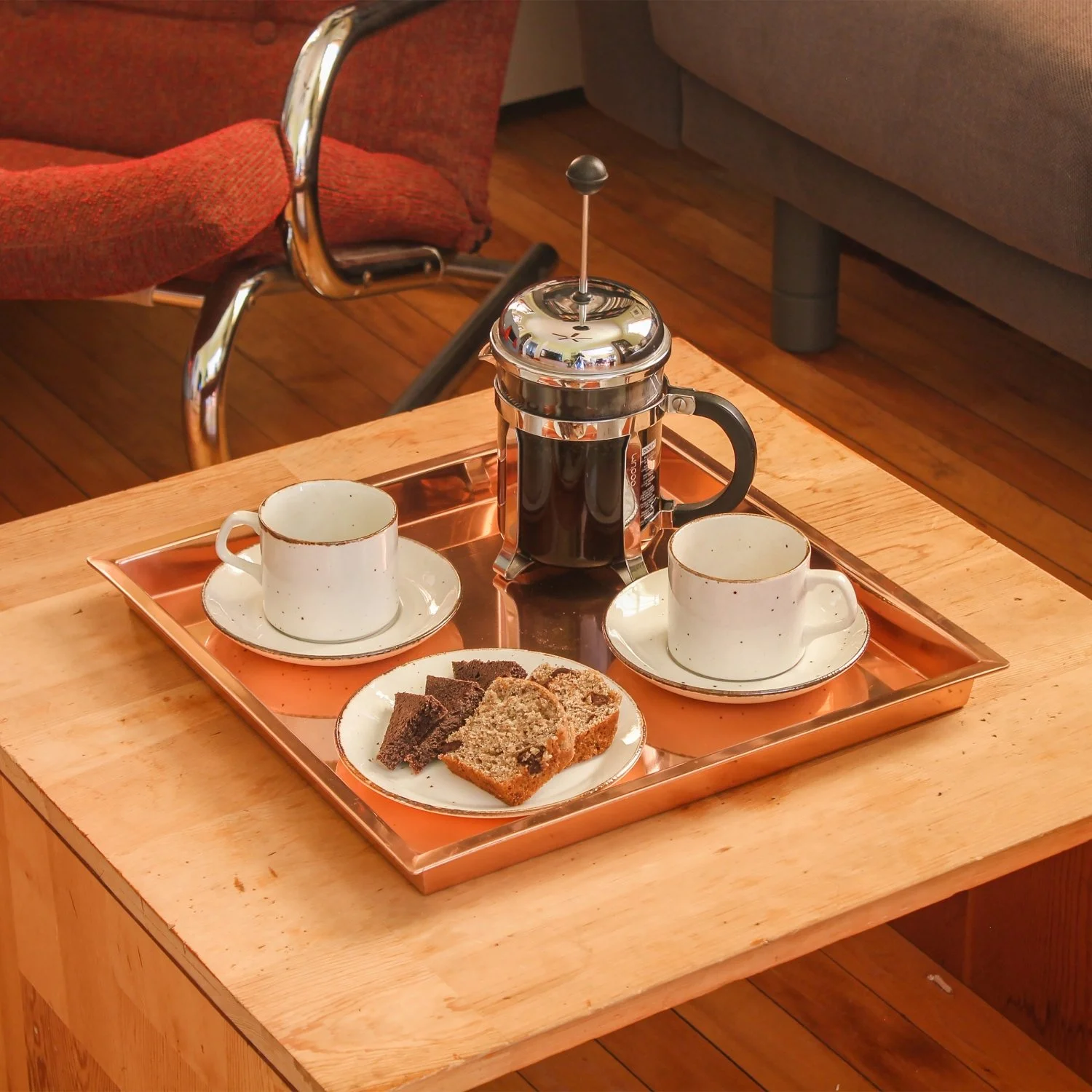 Copper Plated Steel tray with 1 inch walls plated with Coffee and crackers for a party. Tray is resting on a table .