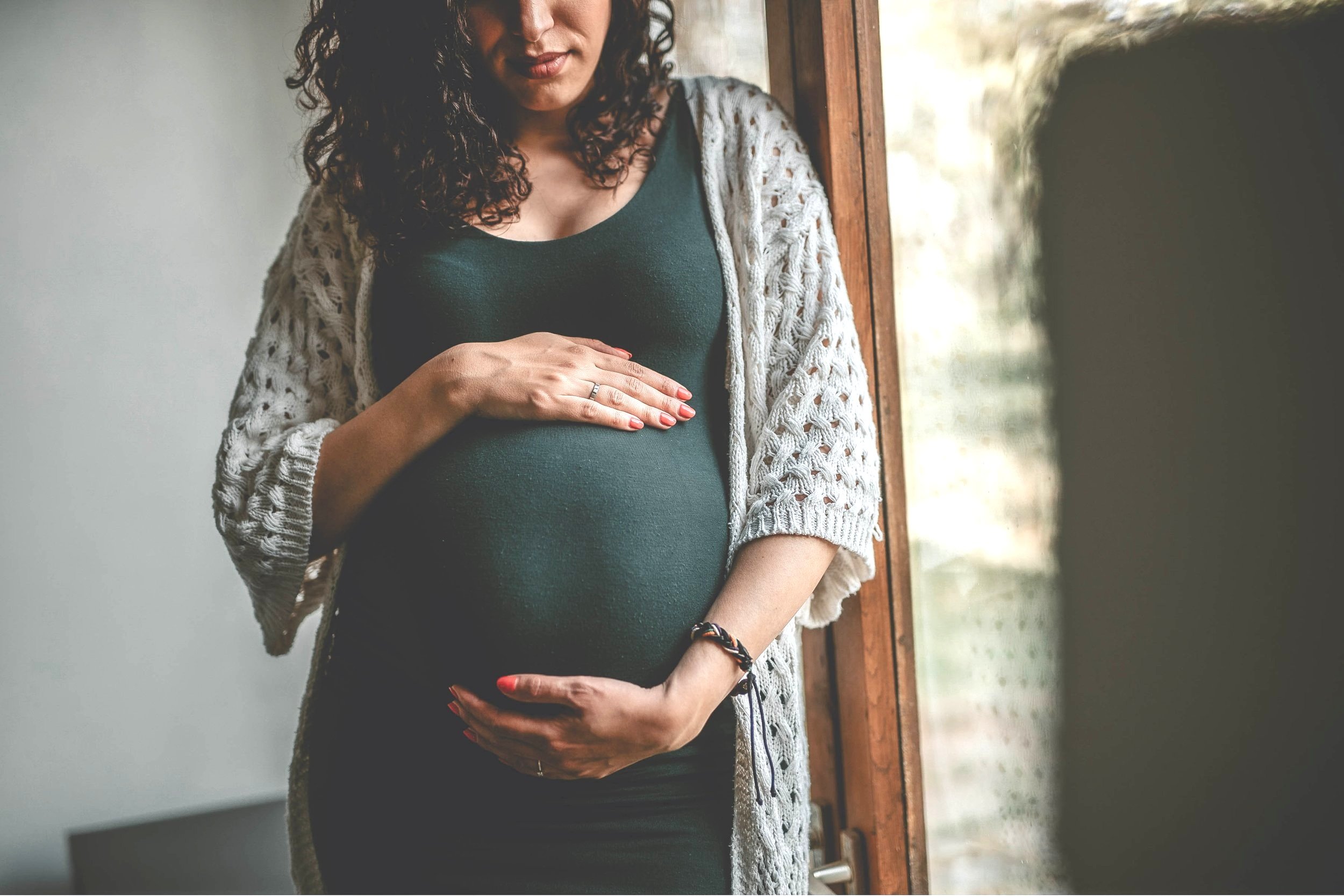 Pregnant mother gently cradling her belly, preparing for breastfeeding and motherhood