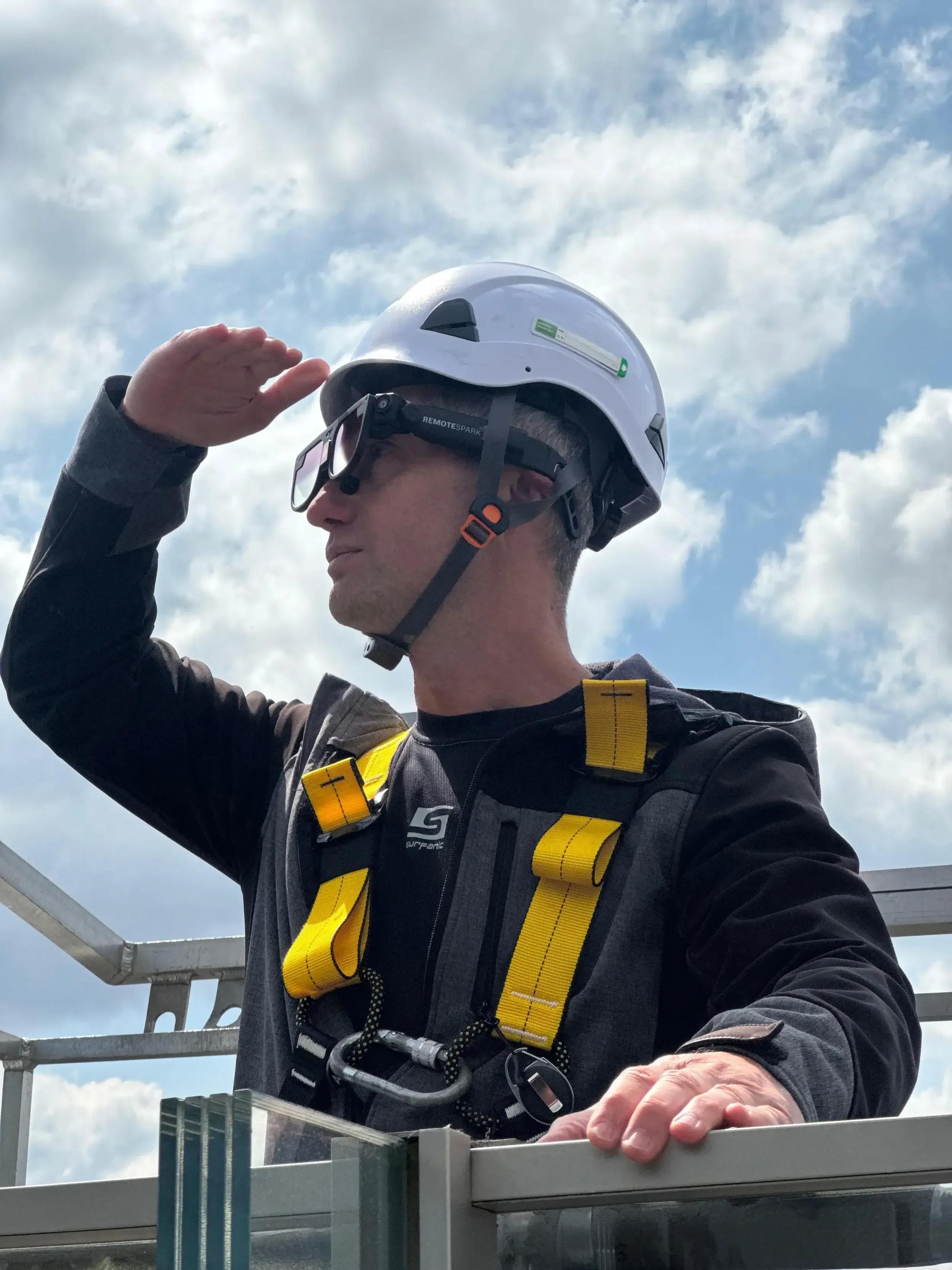 A man wearing a hardhat, equipped with a harness and augmented reality glasses using RemoteSpark