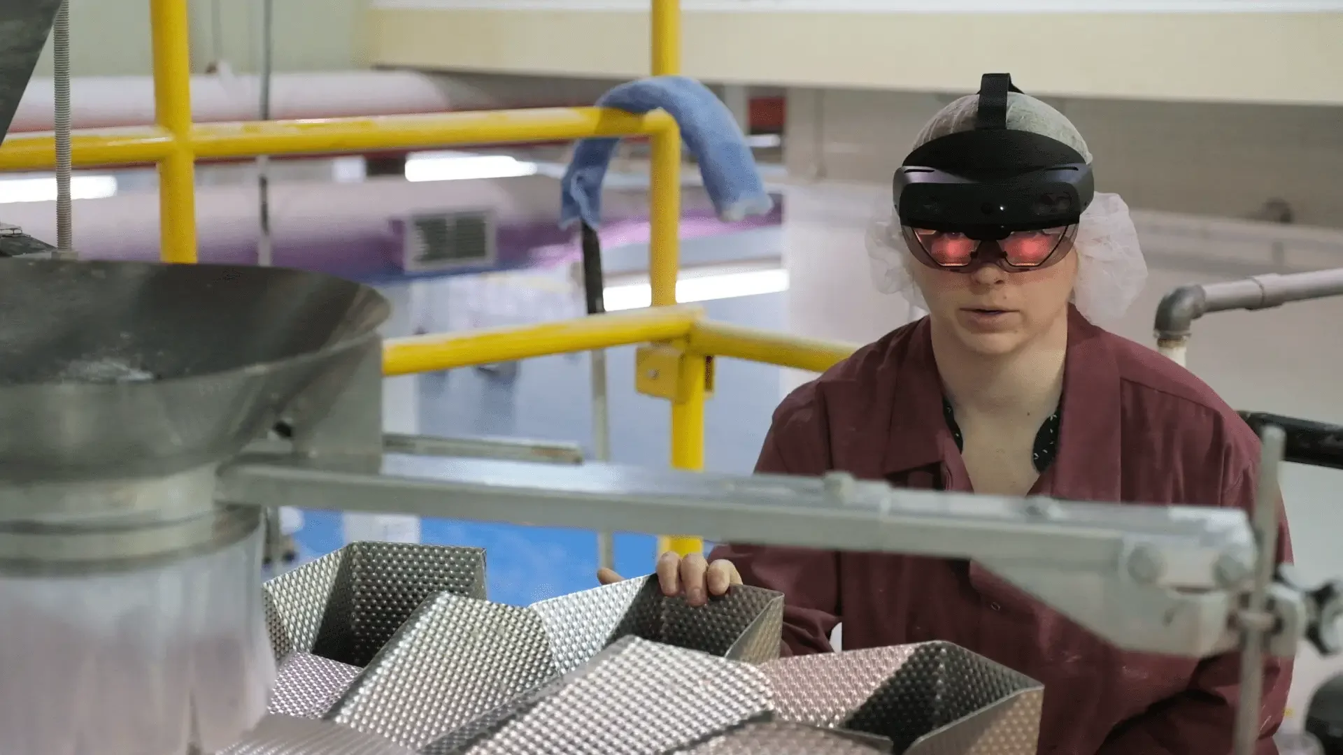 A women wearing a Microsoft HoloLens 2 using RemoteSpark on a piece of equipment in a factory setting