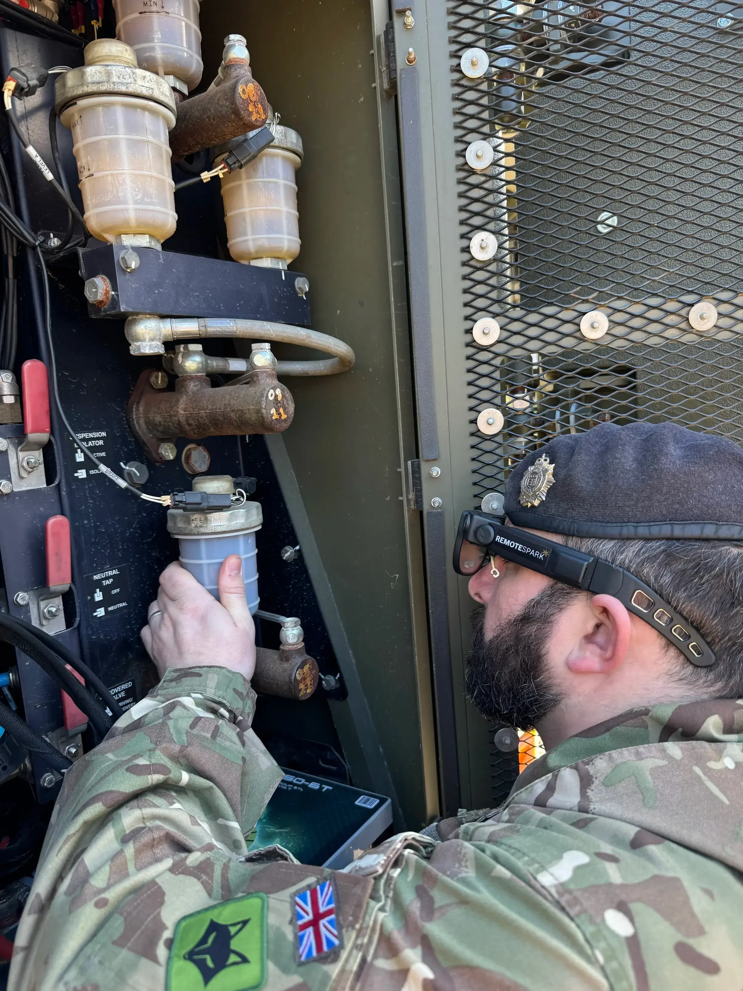 a uniformed man equipped with augmented realtiy glasses inspecting a piece of equipment using RemoteSpark