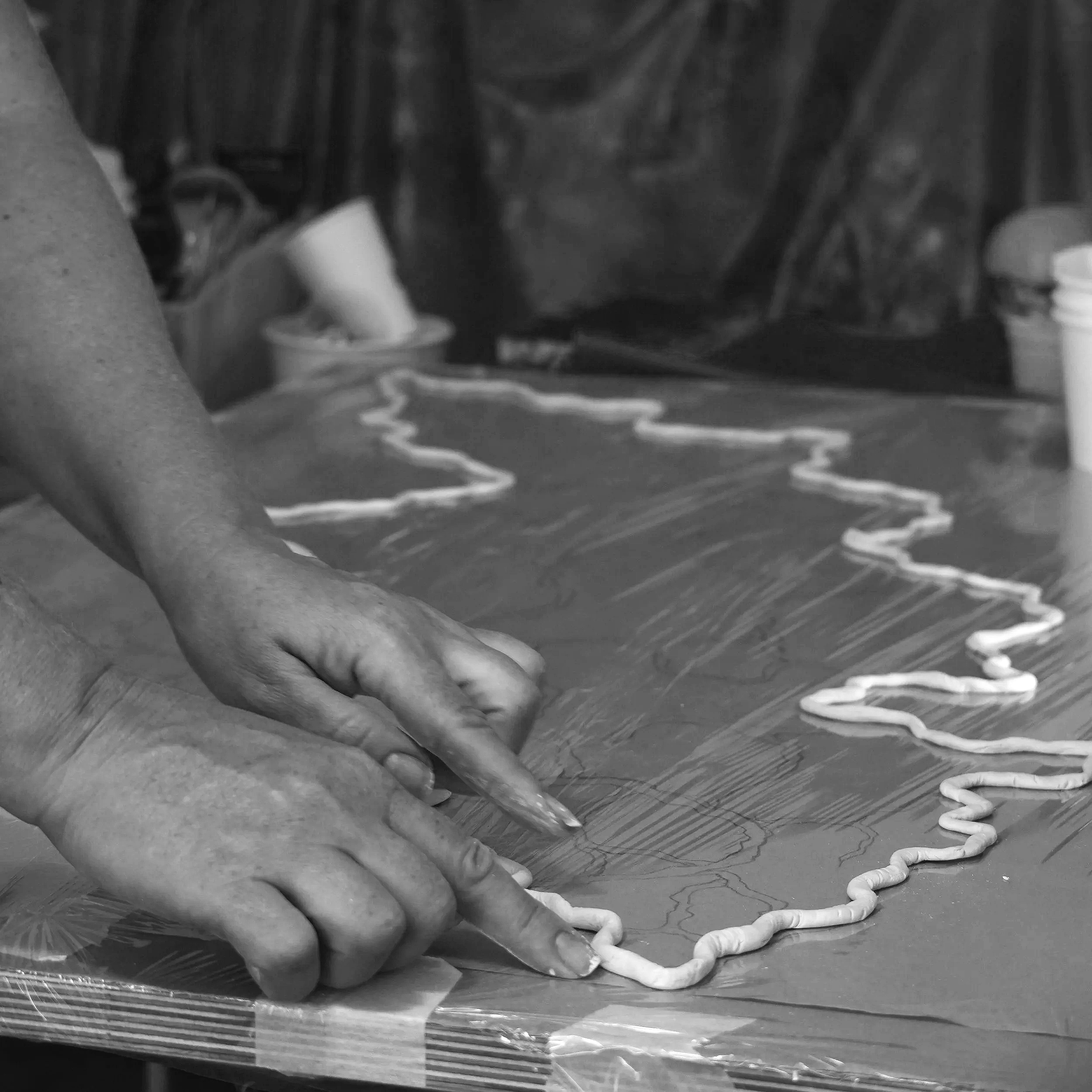 Lé working on a layered mixed-media artwork.