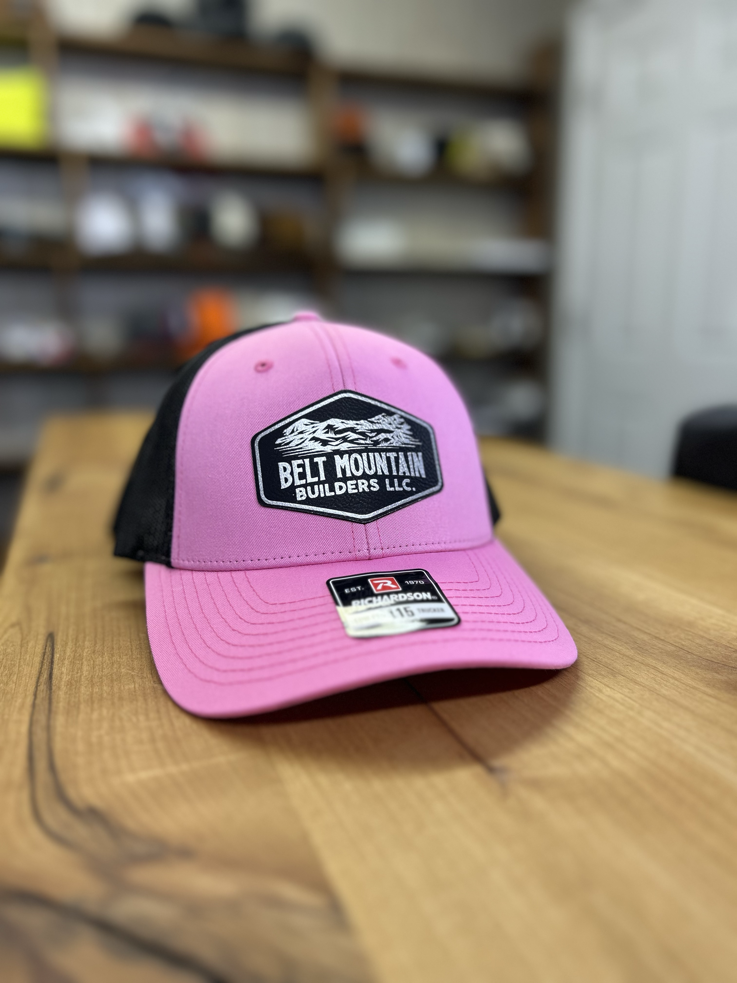 Trucker hat with a leather patch featuring the logo for Belt Mountain Builders.