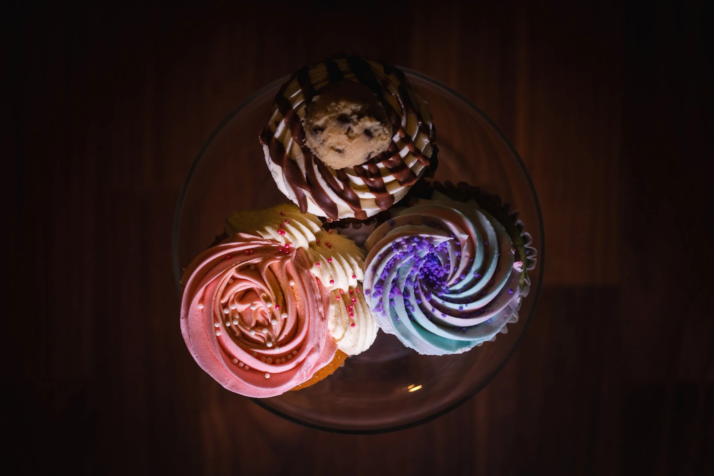 Cookie Dough Cupcake (top); Strawberry Vanilla Cupcake (left); Cotton Candy Cupcake (right)