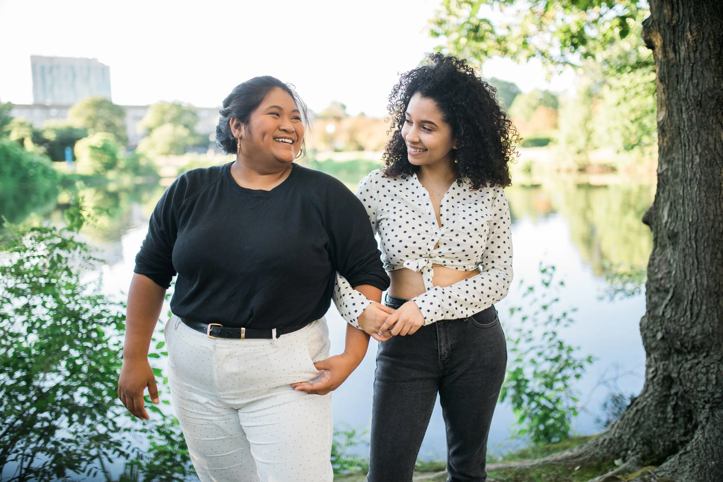 Two women walking together arm in arm and smiling, representing the peace that comes from body acceptance. Therapy in Los Angeles for body image is available to assist in your body positivity journey! 90015 | 90277 | 90401