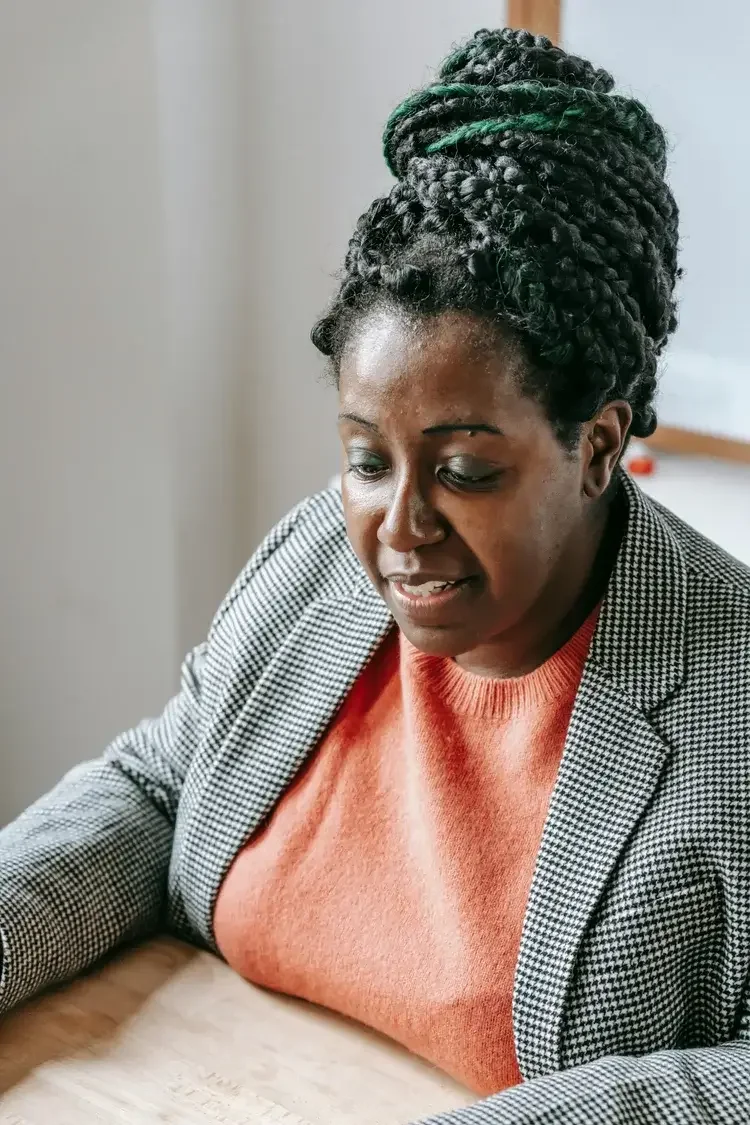 Middle aged Black woman in an orange top and grey blazer. Reach out for a grief therapy consultation, book support for loss and healing. 90094 | 90274 | 90266
