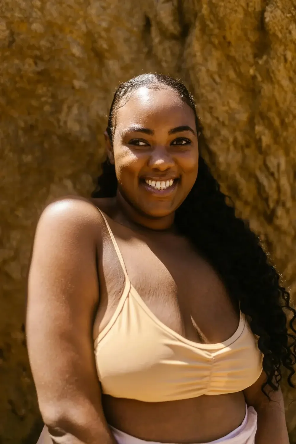 Photo of a midsized Black woman wearing a yellow vest smiling with wood from a tree behing her, representing all the wonderful things that women and people of all genders can do when they accept their body. 90094 | 90266 | 90402