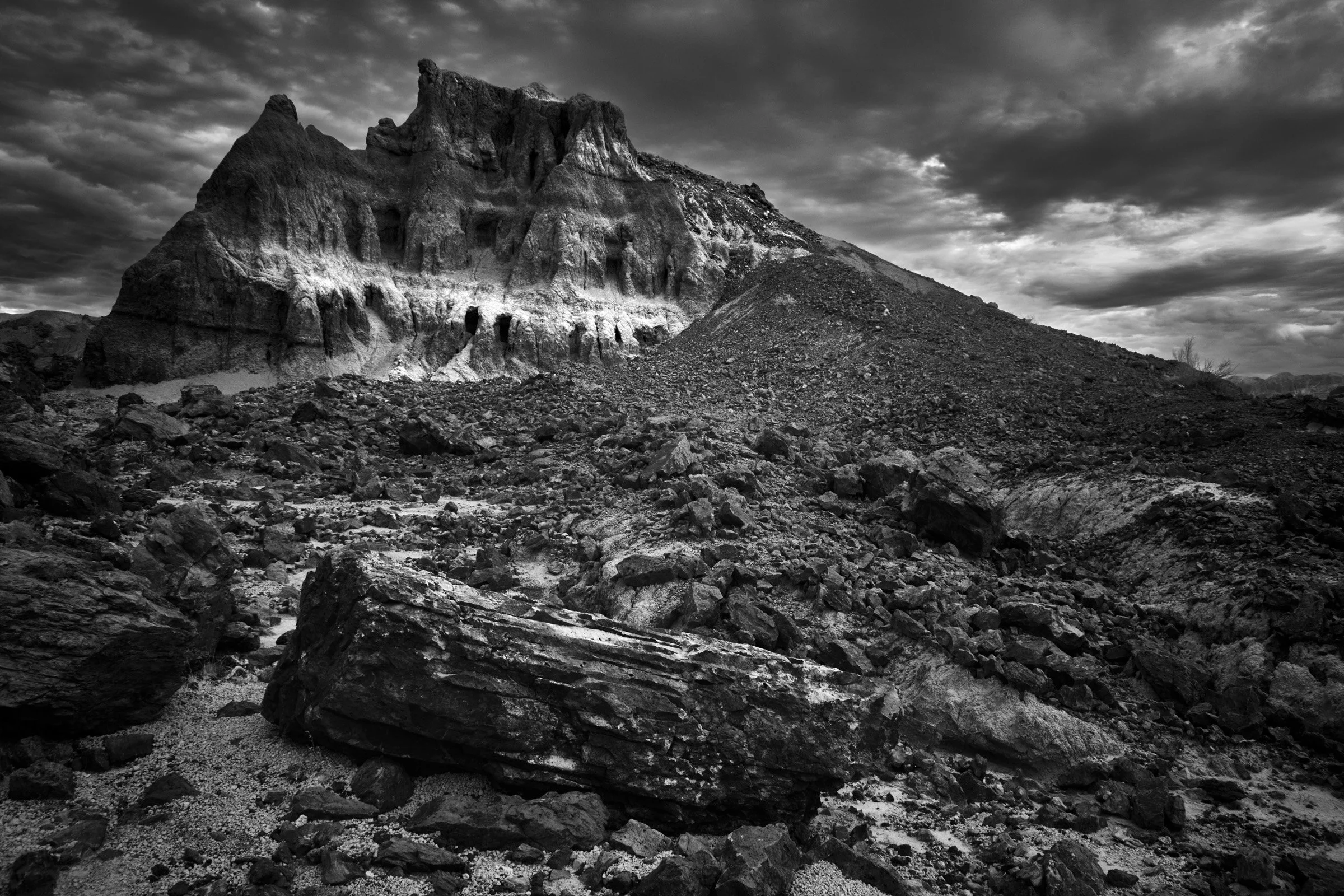 White Scar on the Butte - The face of the butte is cut by a light band, and the ground below is all collapse—stones stacked by gravity into a wide, uneven field at Big Bend.