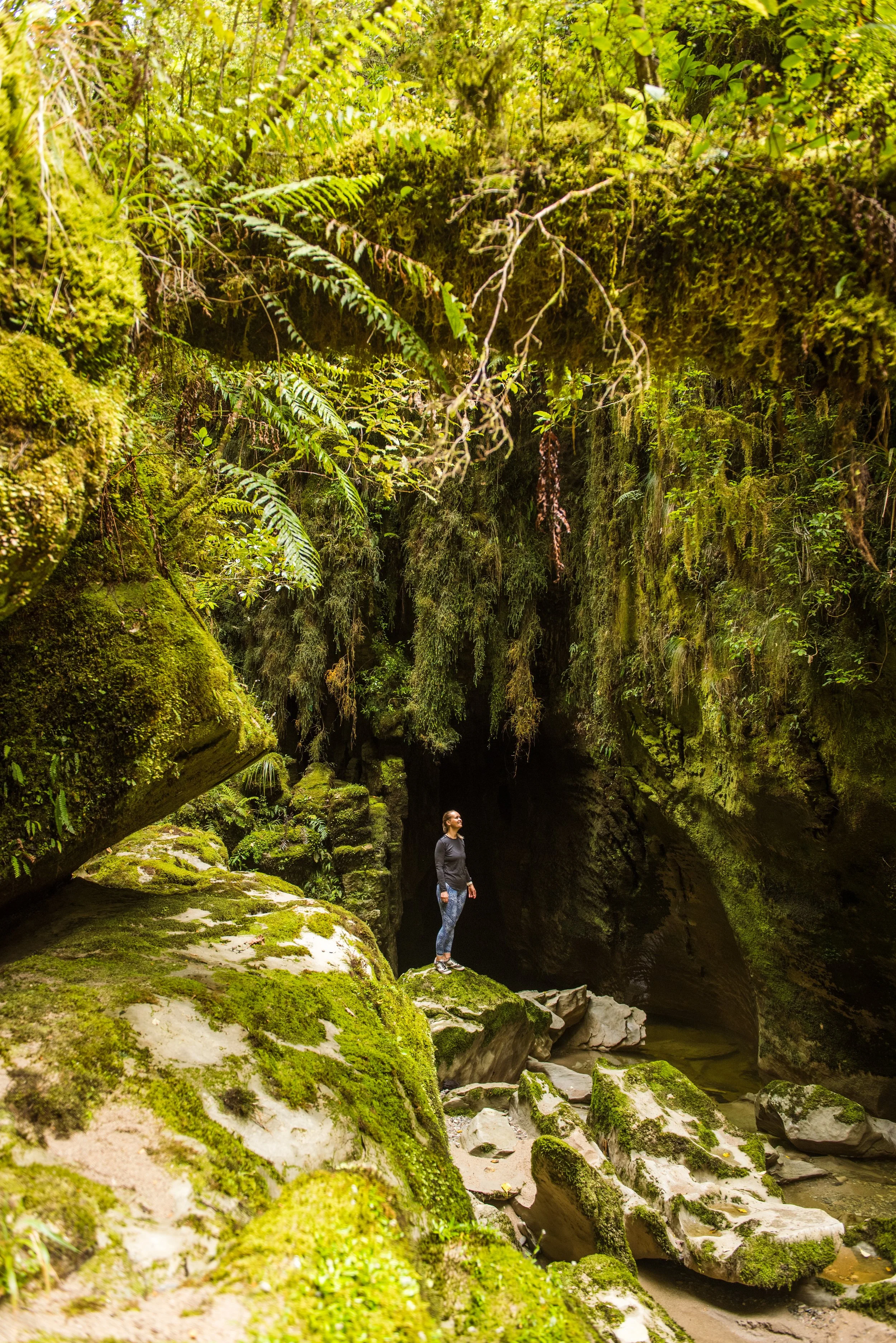 Women standing in cave creek by cliff