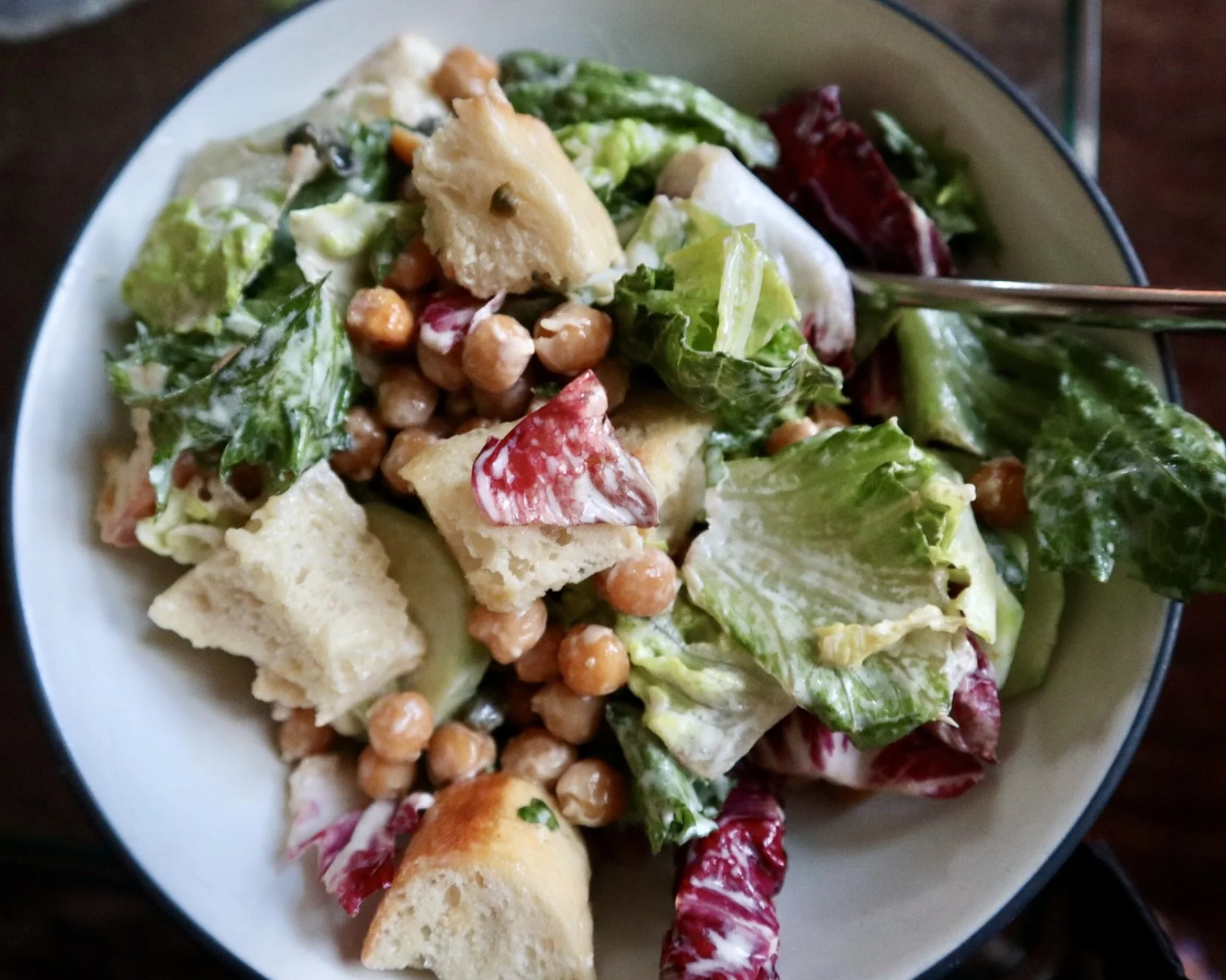 Close-up of a bowl of mixed salad with lettuce, chickpeas, croutons, and radicchio.